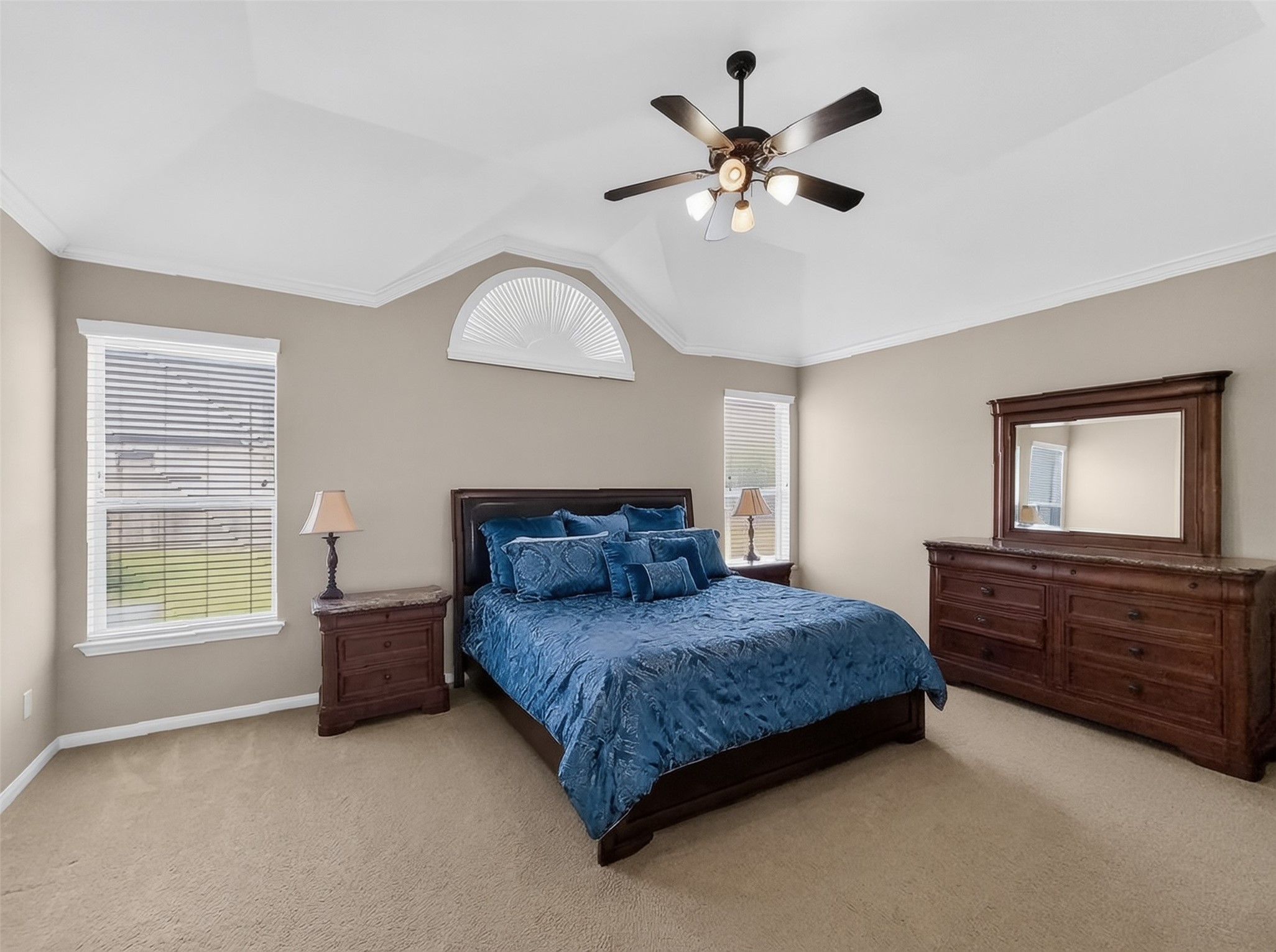 Spacious bedroom with elegant tray ceiling, abundant natural light, and rich wood furniture, creating a serene retreat.