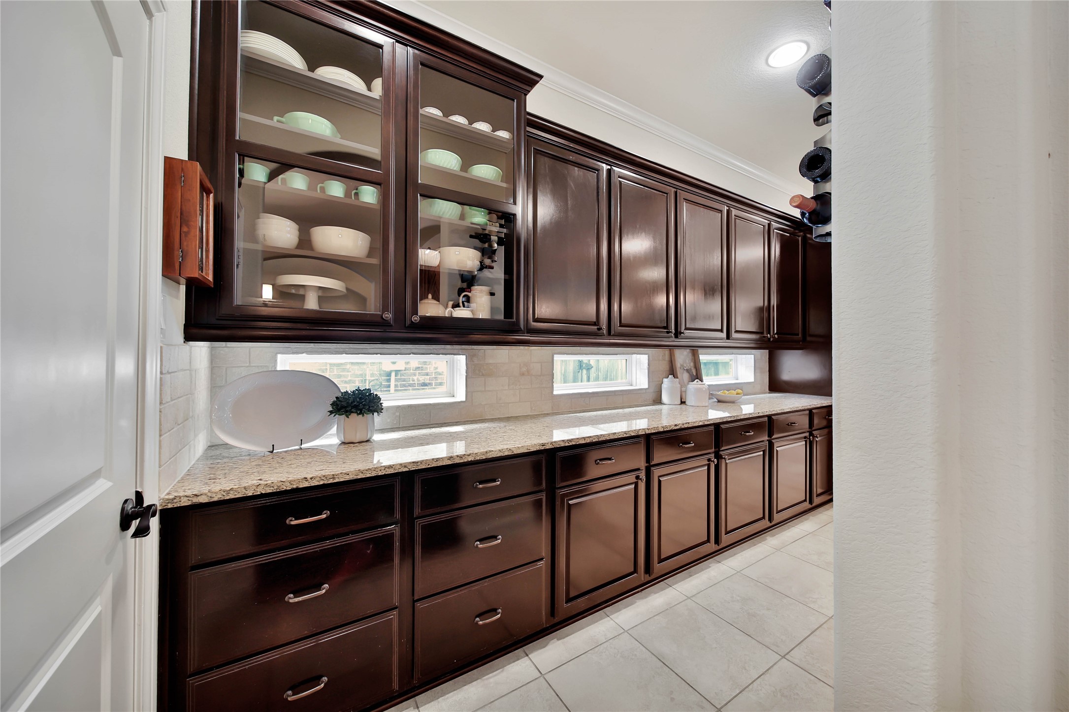 The butlers pantry features elegant glass-front cabinets and flows seamlessly into a buffet-style counter, offering abundant storage and serving space. This thoughtfully designed area is perfect for entertaining guests and displaying your favorite pieces.