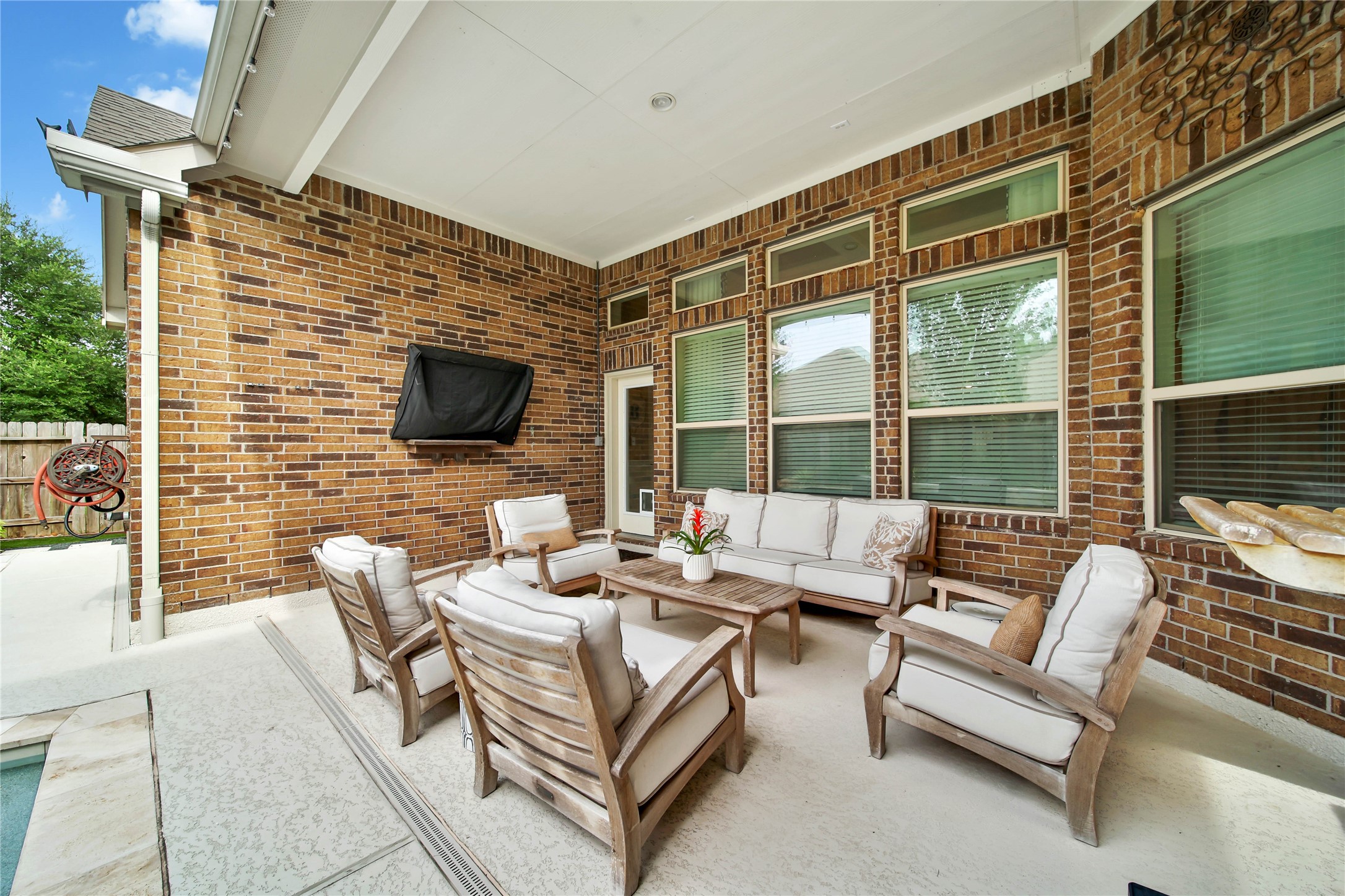Step out into the backyard and relax under the covered patio, one of two inviting seating areas designed for outdoor enjoyment. Both Outdoor TVs can stay!