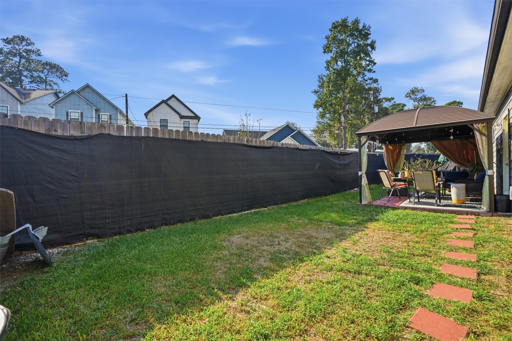 Backyard retreat featuring a cozy gazebo with outdoor seating, perfect for relaxation and entertaining.