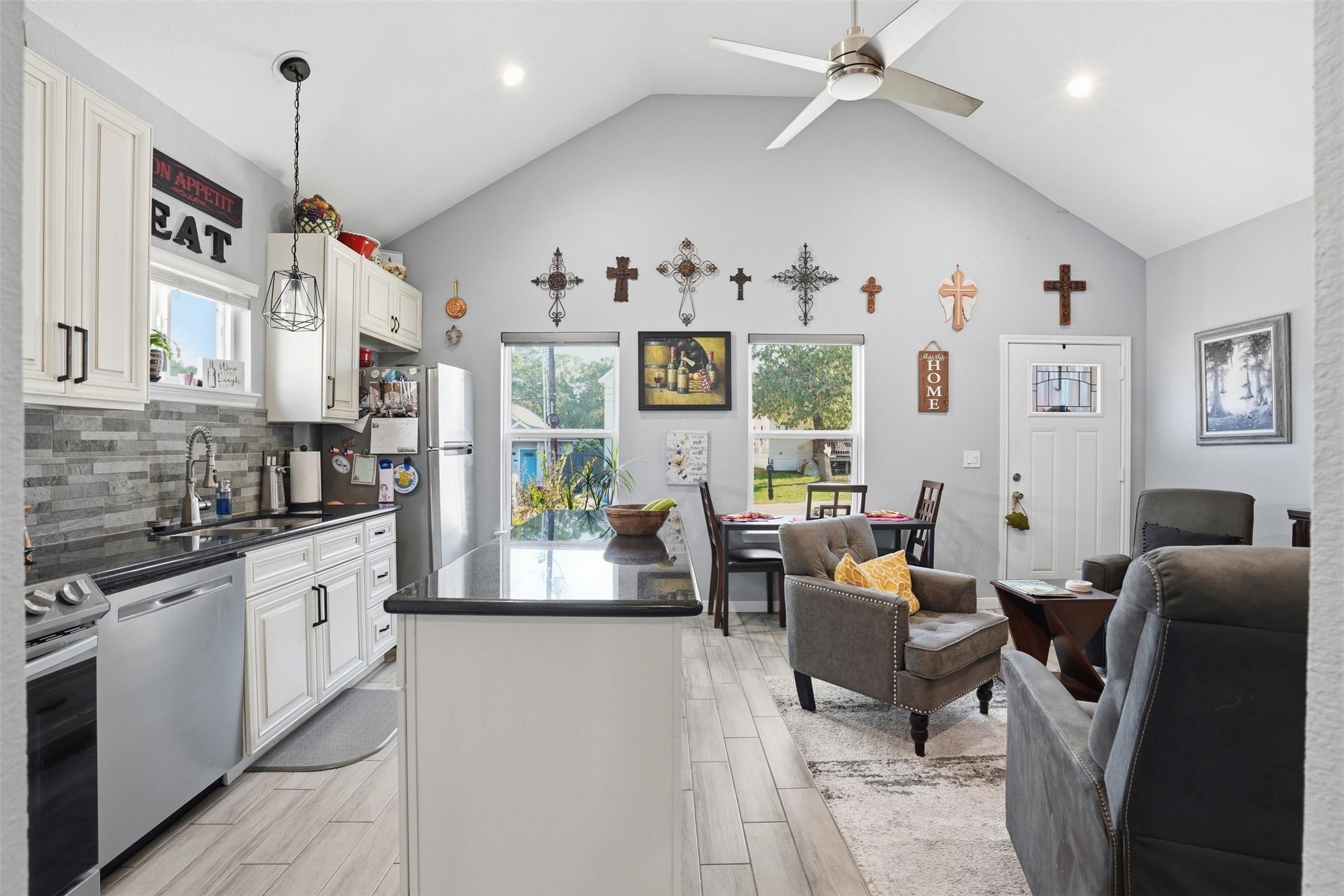 Open-concept living space with vaulted ceilings, featuring a modern kitchen with stainless steel appliances and a cozy seating area.