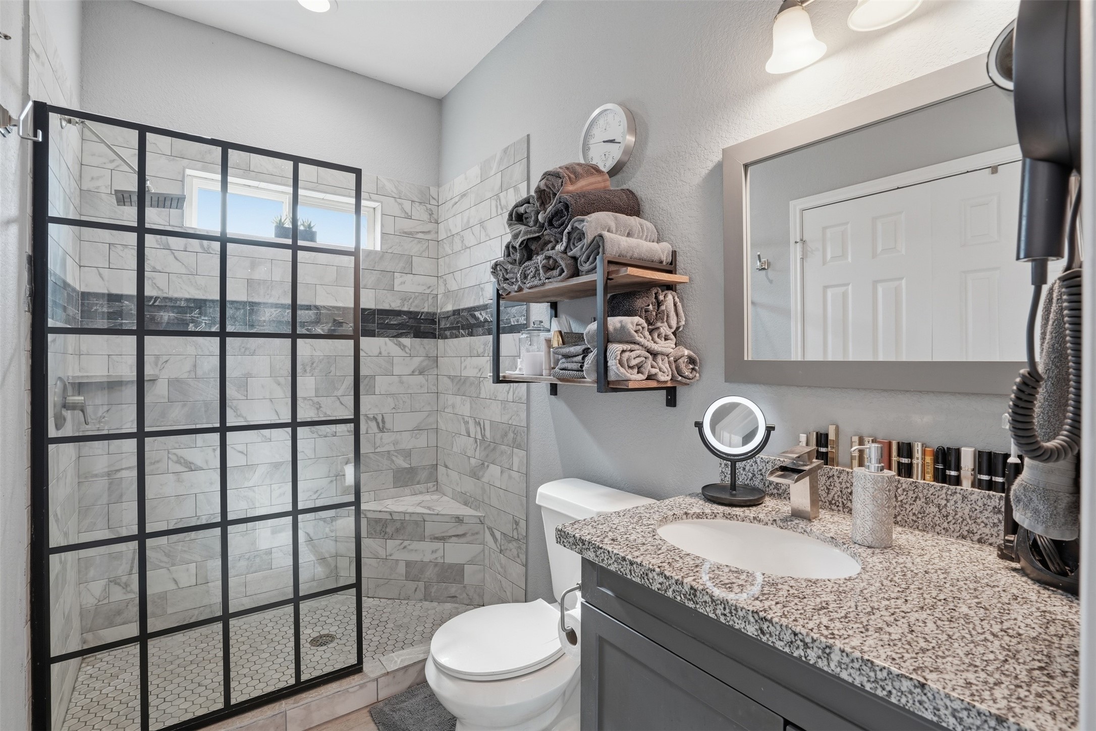 Modern bathroom with a stylish glass-enclosed shower, marble tile backsplash, and a granite countertop.