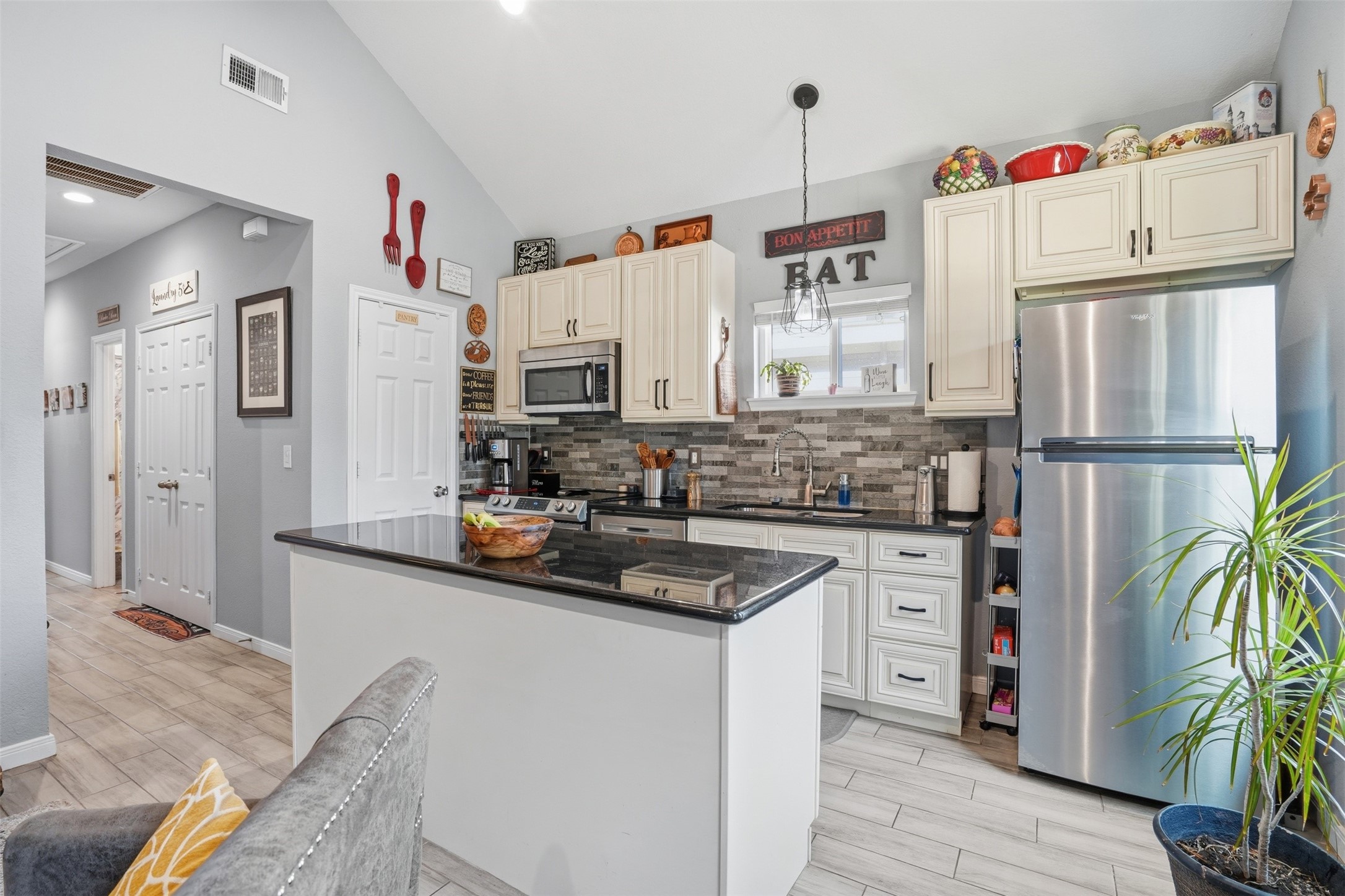 Kitchen with modern stainless steel appliances, elegant cabinetry, and a stylish tile backsplash. The breakfast bar and abundant natural light create a welcoming atmosphere.