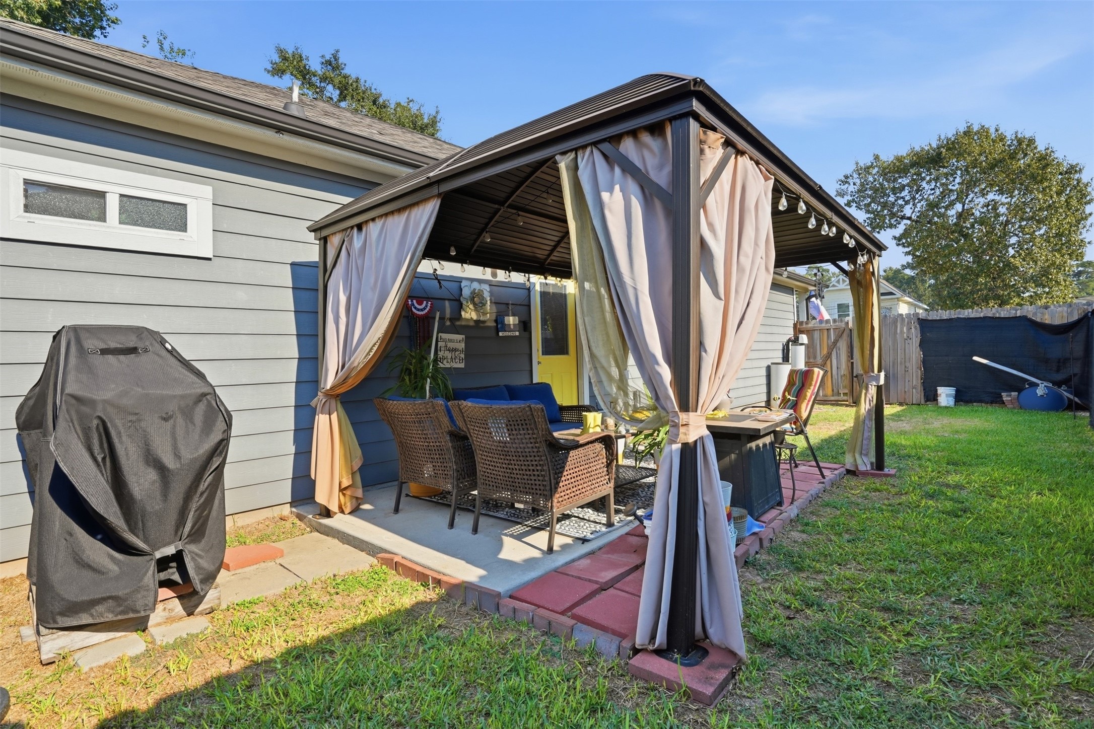 Backyard retreat featuring a cozy gazebo with curtains, perfect for outdoor relaxation and entertaining.