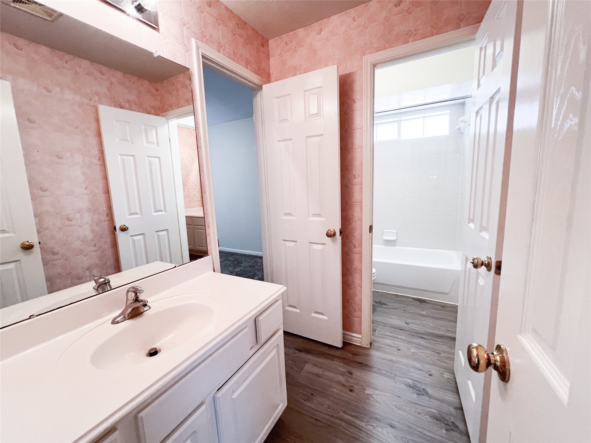 Discover the charm of this inviting second-floor bathroom, featuring elegant pink wallpaper, a pristine white vanity, and a full bathtub for ultimate relaxation.