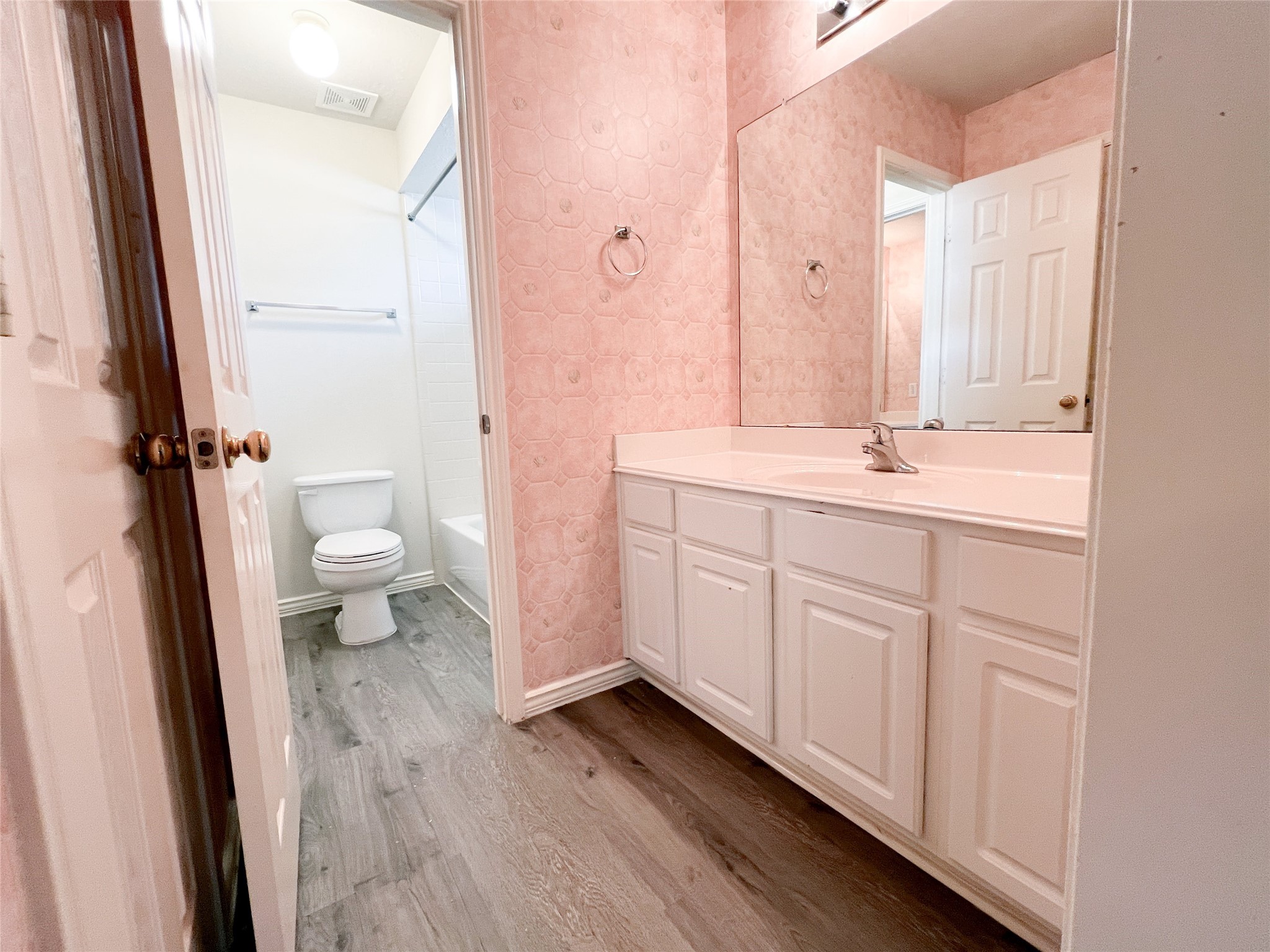 Charming second-floor bathroom featuring a spacious vanity, elegant wood flooring, and a bright, inviting ambiance.