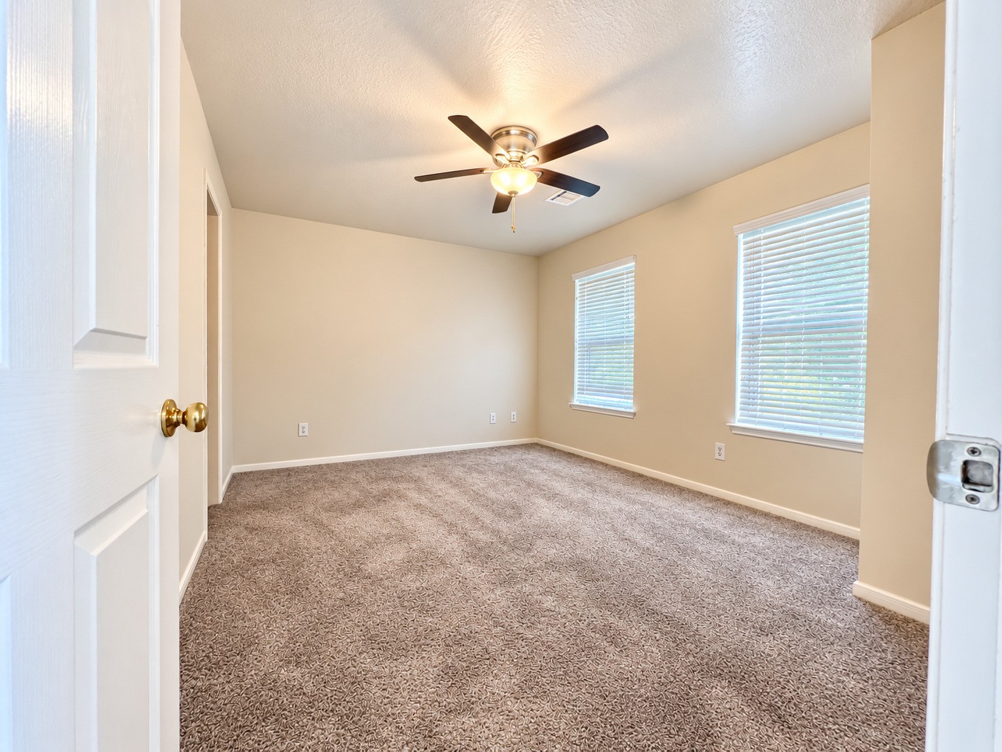Experience comfort in this inviting second-floor bedroom, featuring plush carpeting, ample natural light, and a stylish ceiling fan for a cozy retreat.