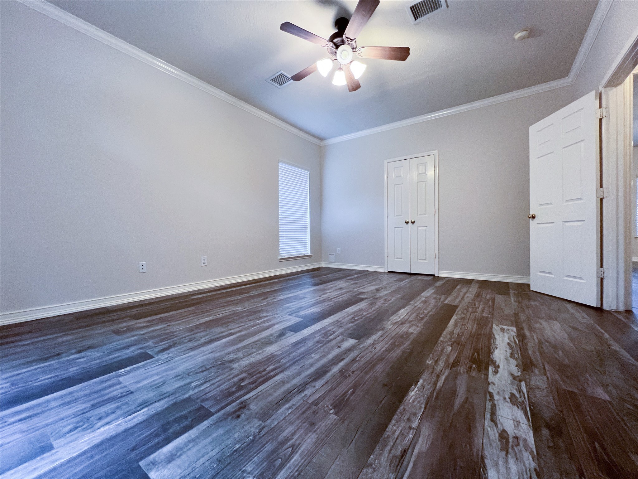 Spacious primary bedroom on the first floor featuring elegant flooring and abundant natural light, perfect for relaxation and convenience.