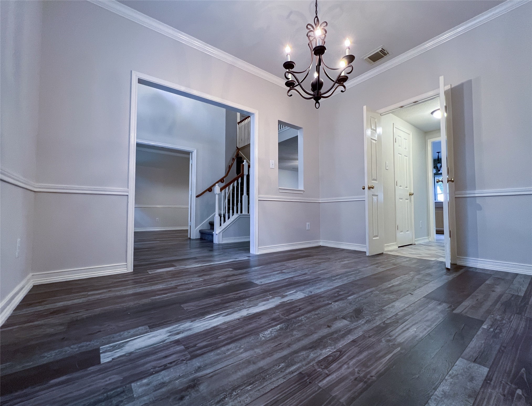 Elegantly designed dining room featuring rich flooring, classic wainscoting, and a stunning chandelier, creating the perfect ambiance for memorable gatherings. Elegantly designed dining room featuring rich flooring, classic wainscoting, and a stunning chandelier, creating the perfect ambiance for memorable gatherings.