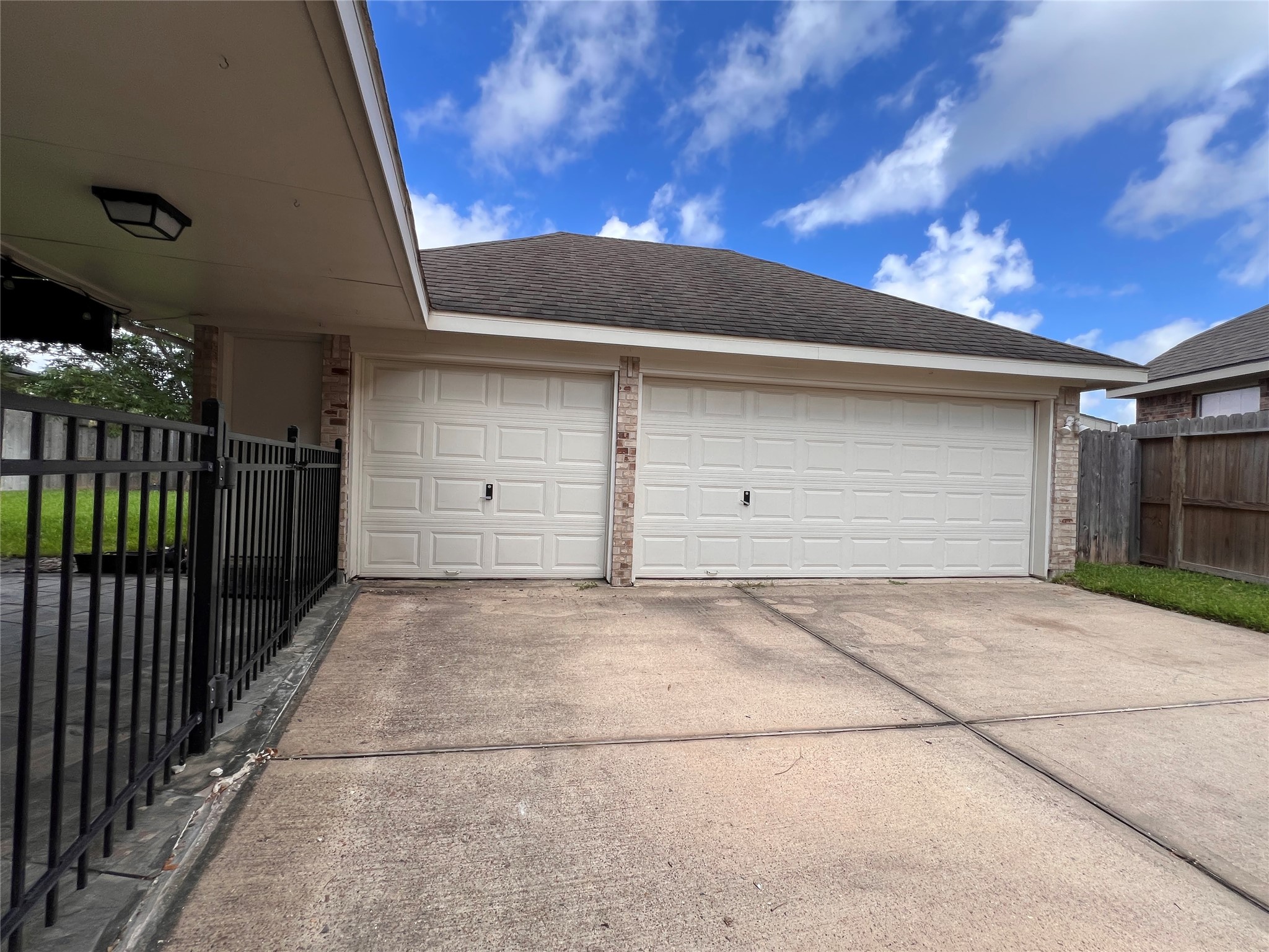 Spacious three-car garage with a wide driveway and secure fencing, ideal for convenient parking and storage.