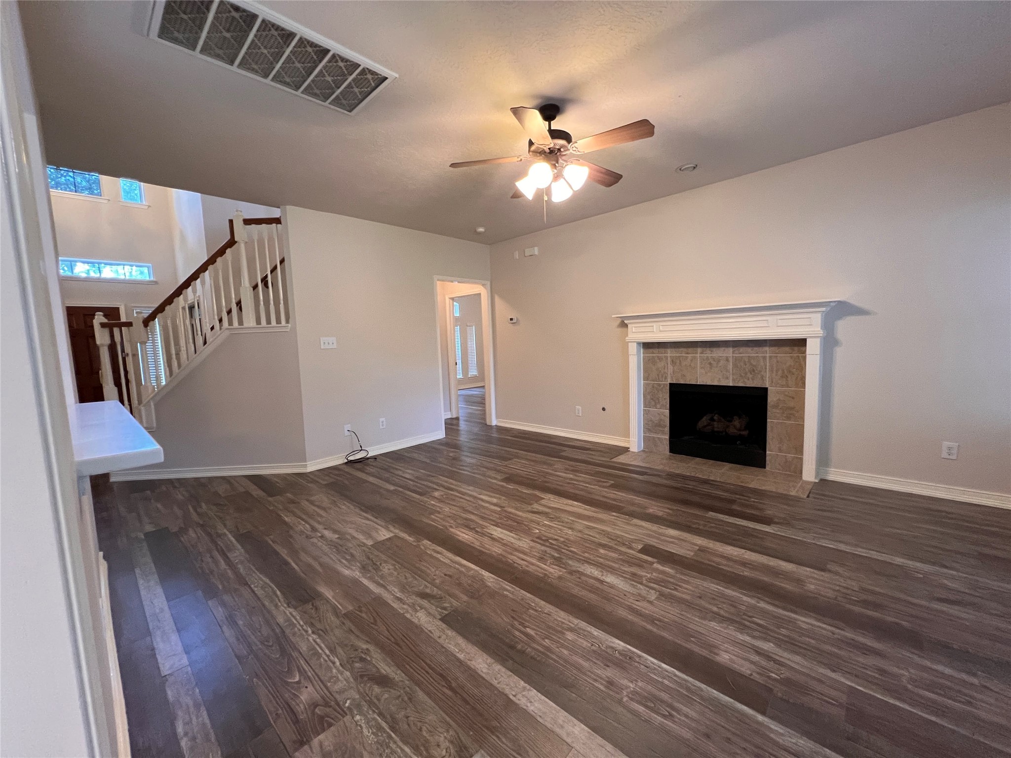 Experience the warmth and elegance of this inviting living area, featuring rich flooring, a cozy fireplace, and a stylish ceiling fan, all beautifully illuminated by natural light from the open staircase and adjacent spaces. Experience the warmth and elegance of this inviting living area, featuring rich flooring, a cozy fireplace, and a stylish ceiling fan, all beautifully illuminated by natural light from the open staircase and adjacent spaces.