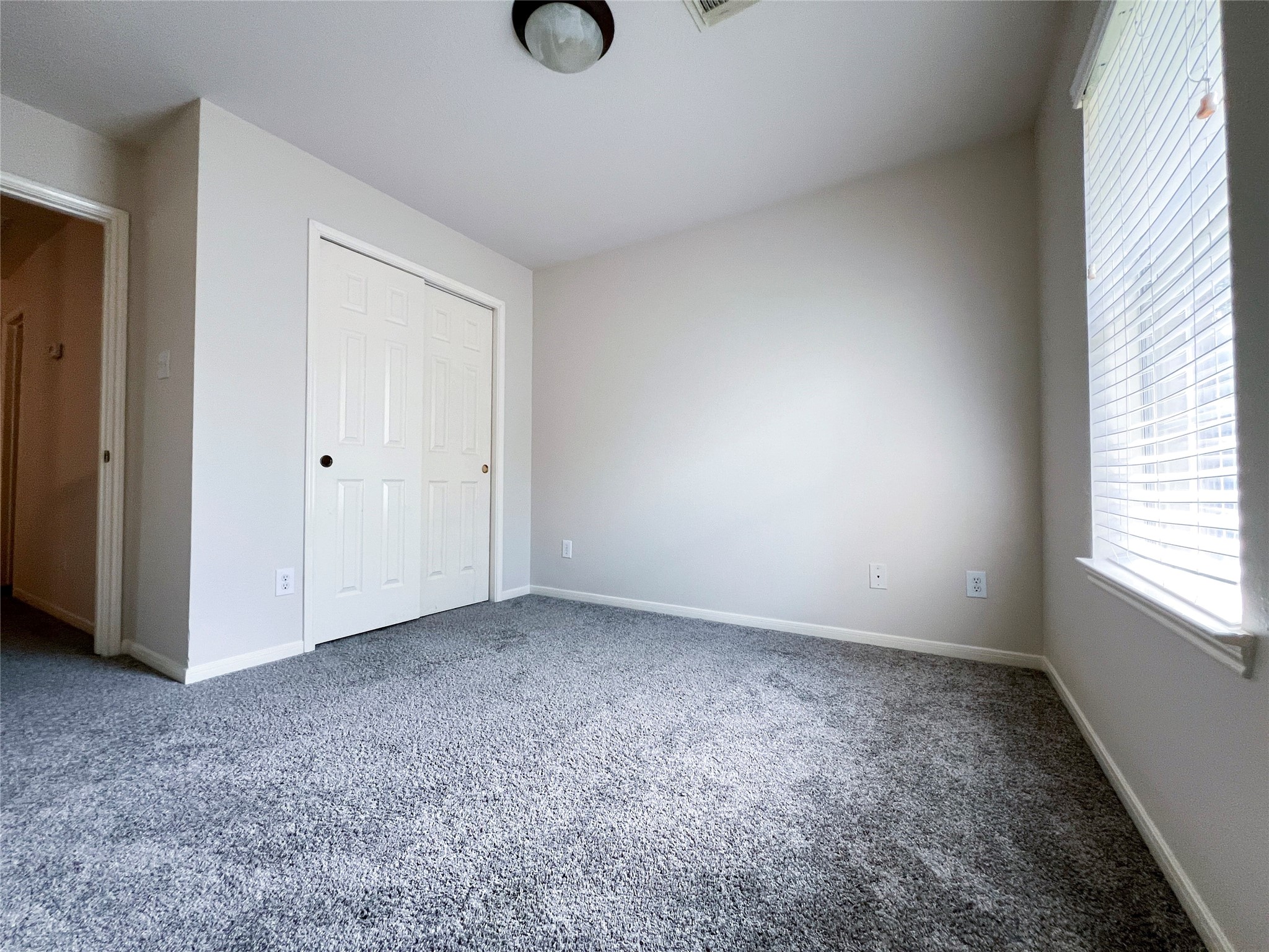 Experience comfort and tranquility in this spacious second-floor bedroom, featuring plush carpeting and abundant natural light.