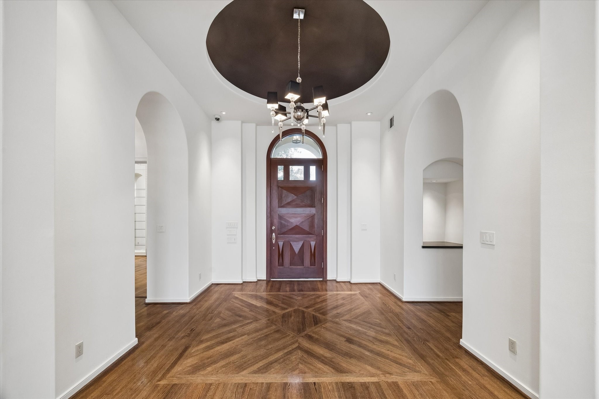 DRAMATIC FOYER WITH DOMED CEILING - accented with elegant lighting fixture, cove lighting in the dome, dual lighted art niches, beautiful hardwood flooring with inlaid design - note the arched entry and arches featured throughout this fine home