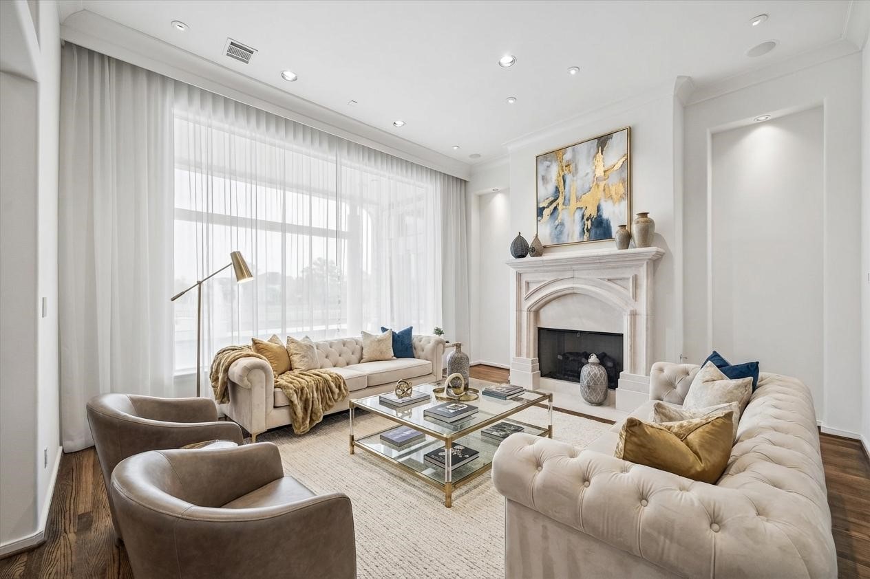 VIRTUALY STAGED - formal living room with high ceiling, dual lighted art niches, gas-log fireplace - sheer draperies framing the large window with views of covered terrace and on to the pool/spa and lake