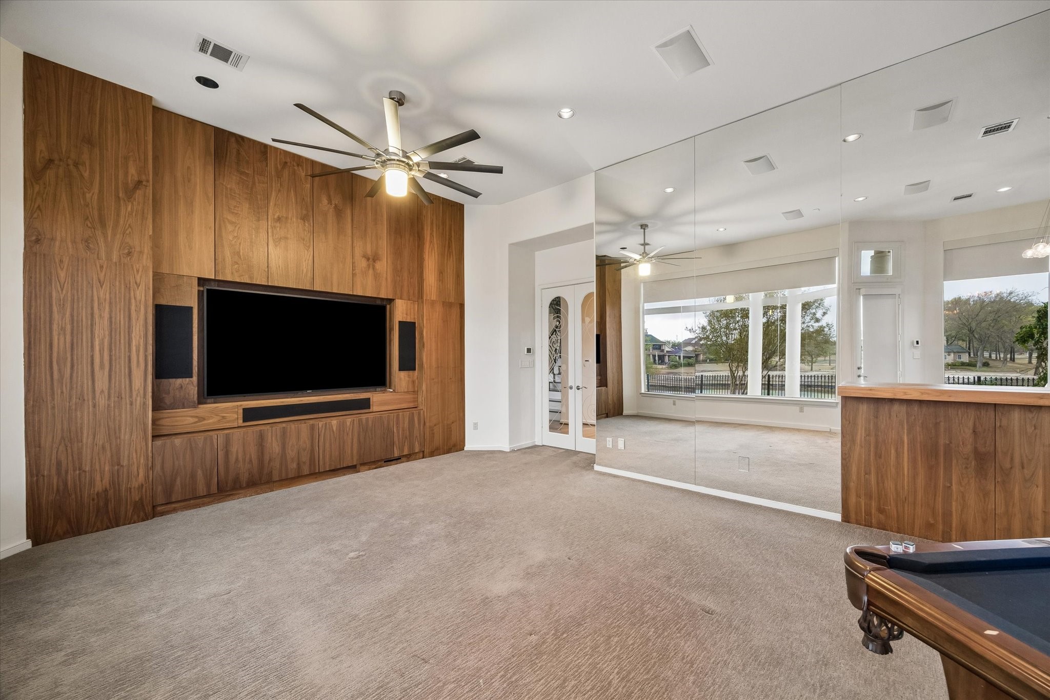 LARGE MEDIA/GAME ROOM DESIGNED FOR RELAXATION AND FUN - beautiful cabinetry with large-screen TV and built-in speakers + abundant storage - double doors with glass insert panels, mirrored wall reflects a serene view of the terrace and out to the lake and golf course - + the pool table is included