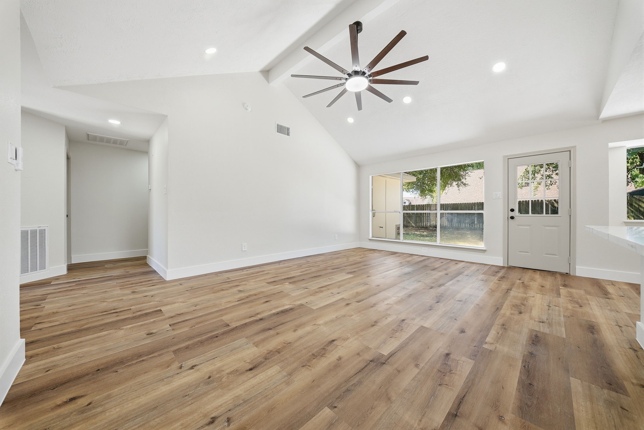 Spacious living area with abundant natural light from large windows with view of and door with access to yard, creating a bright and inviting atmosphere.