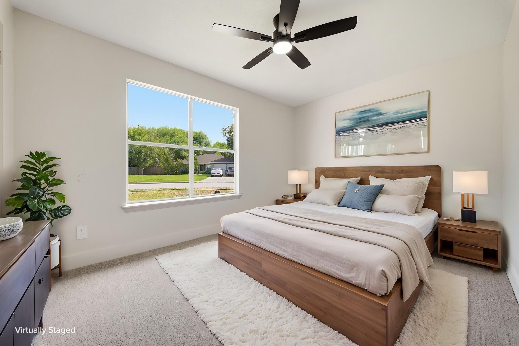 Bright and inviting bedroom with a large window offering plenty of natural light, plush carpeting, a stylish ceiling fan for a cozy atmosphere.