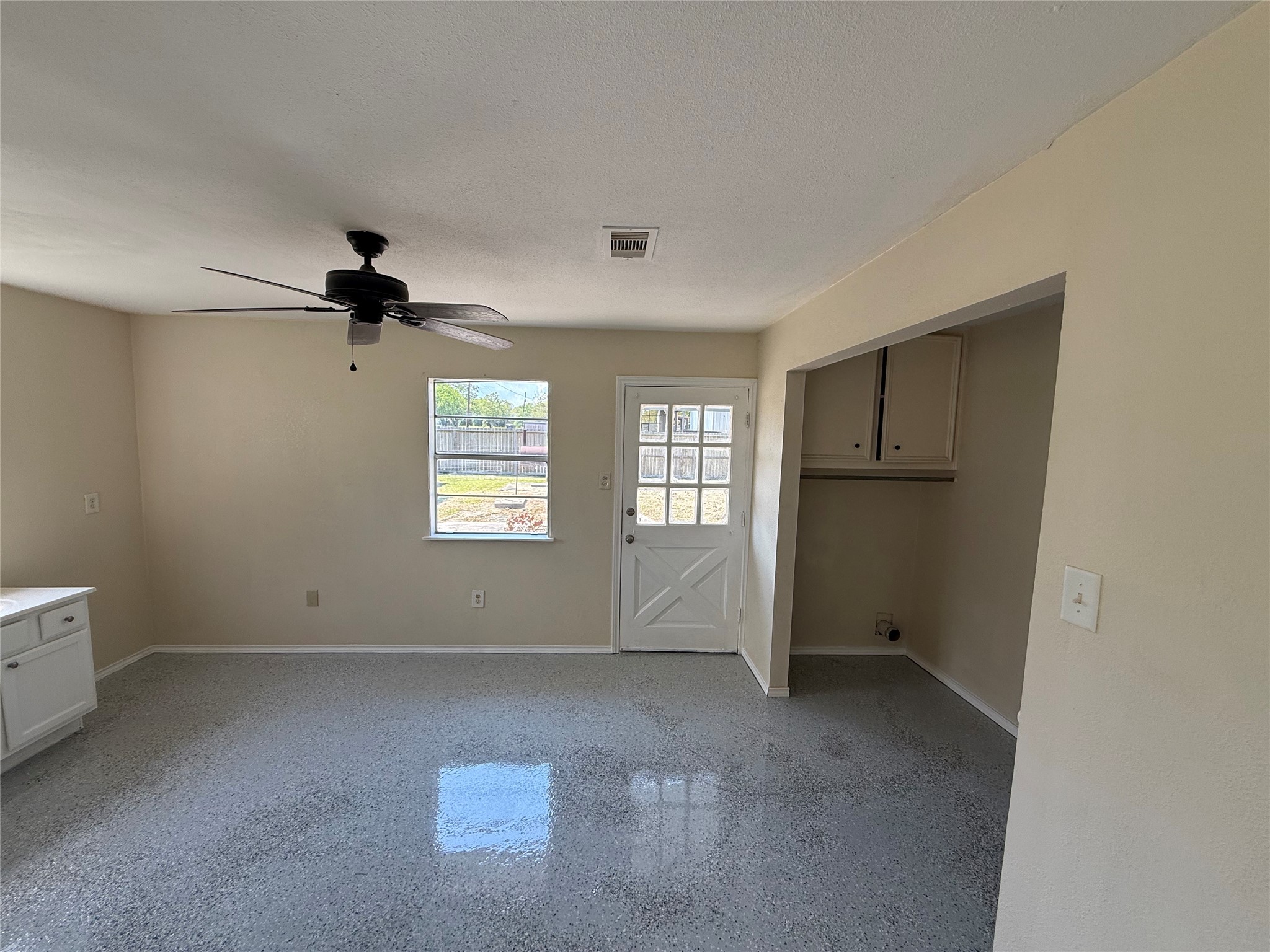 Tiled room with natural light, a ceiling fan, and an adjacent utility alcove.
