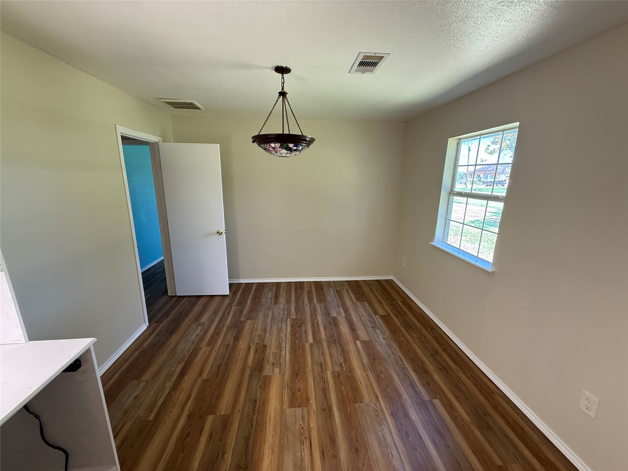 Room with wood-look flooring, a ceiling fan, and a large window.