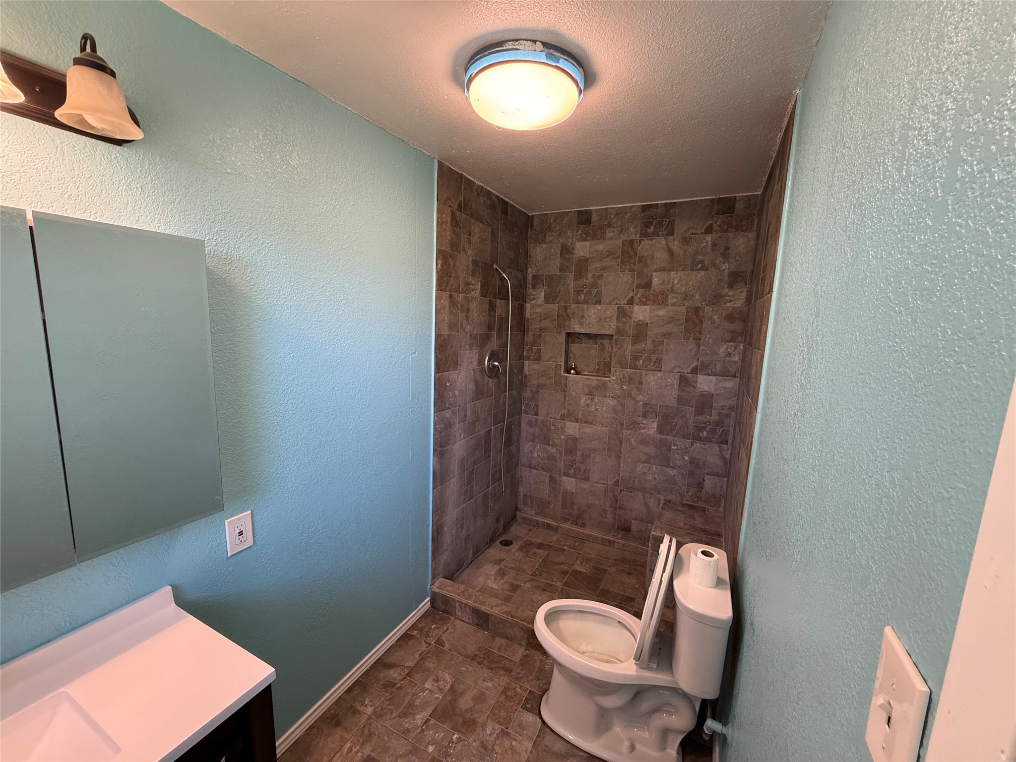 Bathroom featuring a mirrored cabinet and a stone-look accent wall.