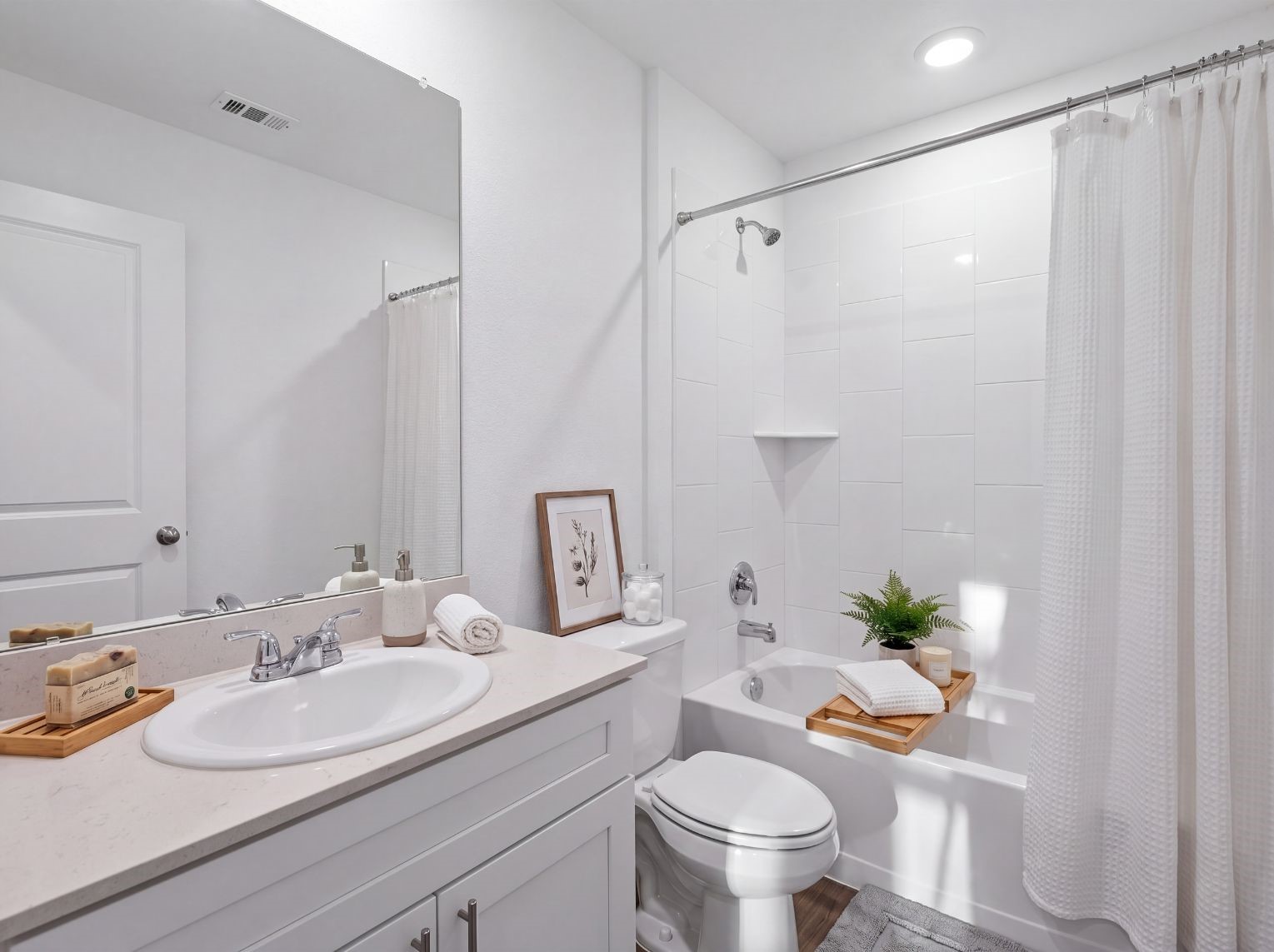Full bath with a single-sink vanity, light stone counter, large mirror, and a tub-and-shower combo with a tall tile surround. Recessed lighting and a built-in corner shelf add function.
This photo has been digitally staged to illustrate the possibilities of the home's aesthetic and potential design. Some furnishings and dcor shown are for visual inspiration.