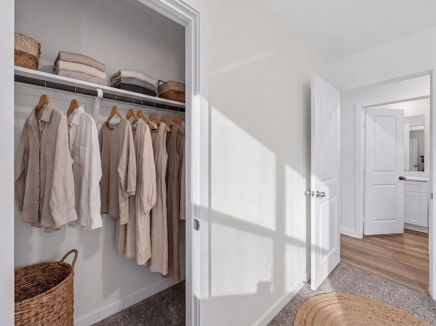 Bedroom closet with hanging space and a shelf, opening to a carpeted bedroom and a hall that leads to the bath. Wood-look flooring runs through the hallway.
This photo has been digitally staged to illustrate the possibilities of the home's aesthetic and potential design. Some furnishings and dcor shown are for visual inspiration.