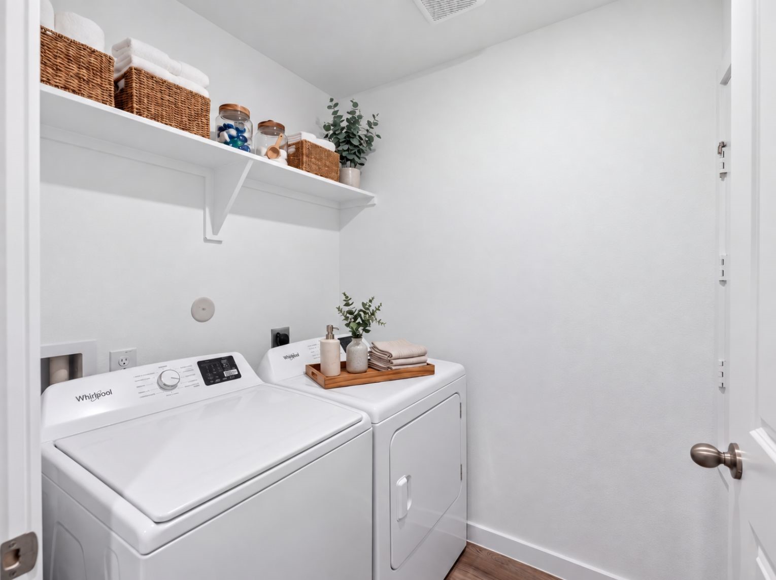 Dedicated laundry room with washer and dryer connections, a built-in storage shelf, and wood-look flooring. A practical, tucked-away space.
This photo has been digitally staged to illustrate the possibilities of the home's aesthetic and potential design. Some furnishings and dcor shown are for visual inspiration.