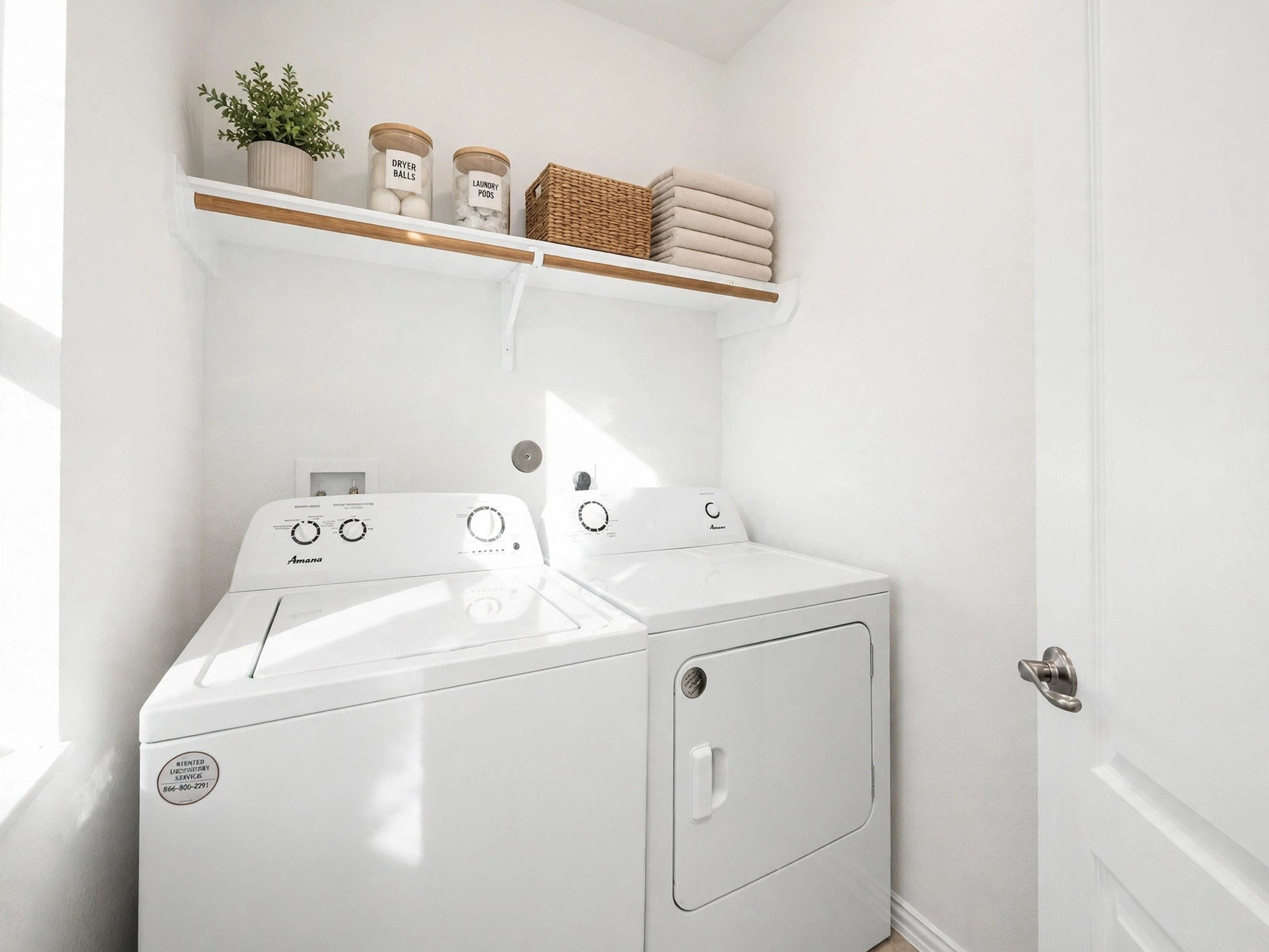Dedicated laundry room with washer and dryer connections and overhead shelving.