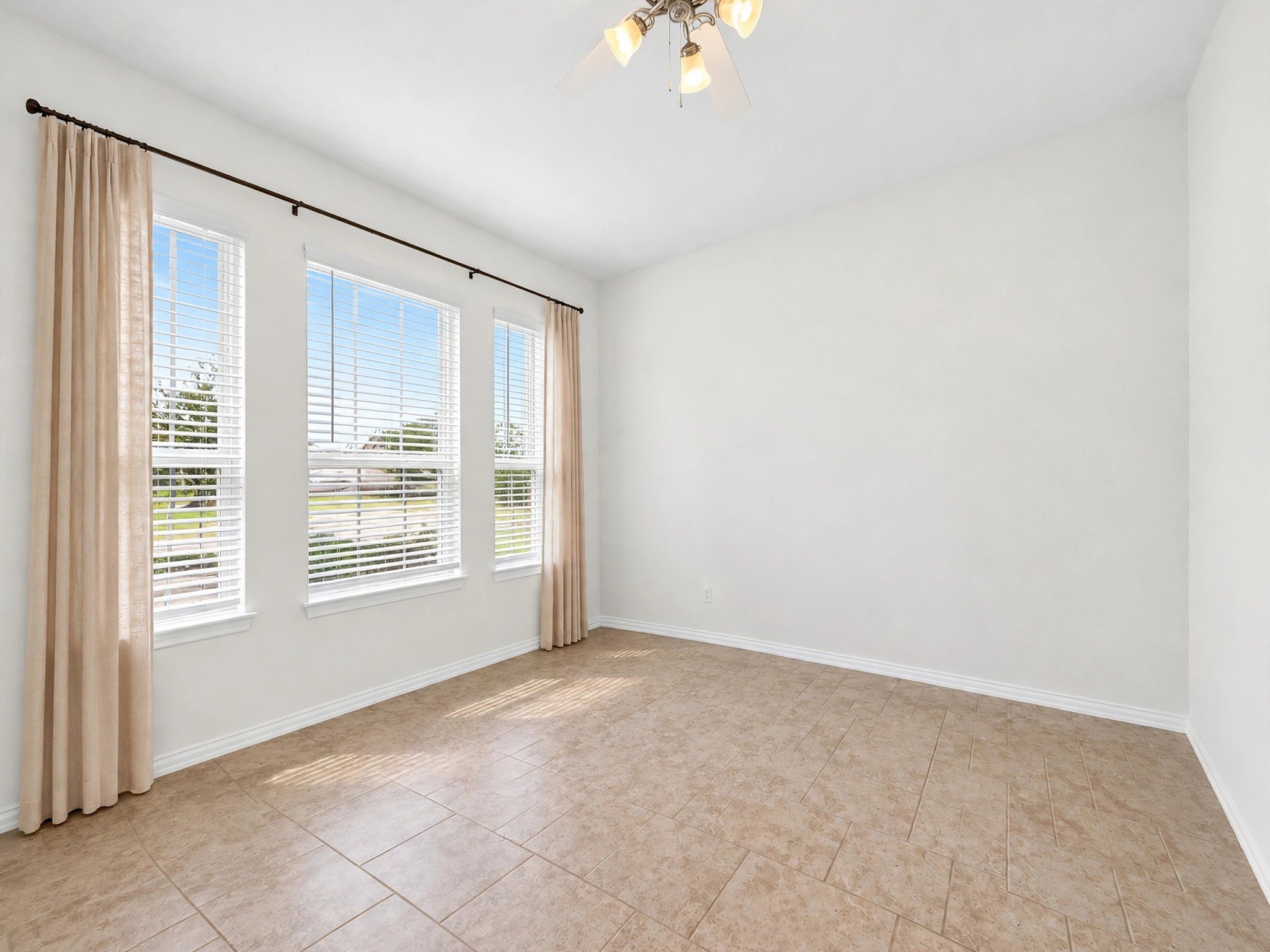 Unfurnished view highlights this rooms tile flooring, large windows, and flexible layout.