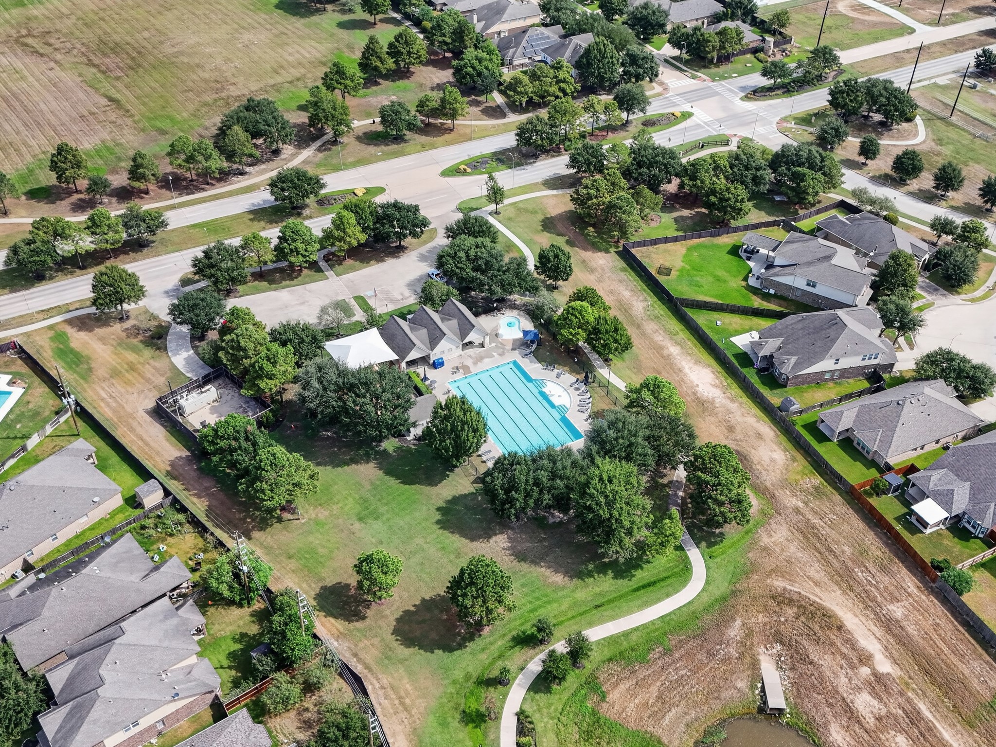 Aerial view showcases a neighborhood recreation area with a pool, green space, and surrounding homes.