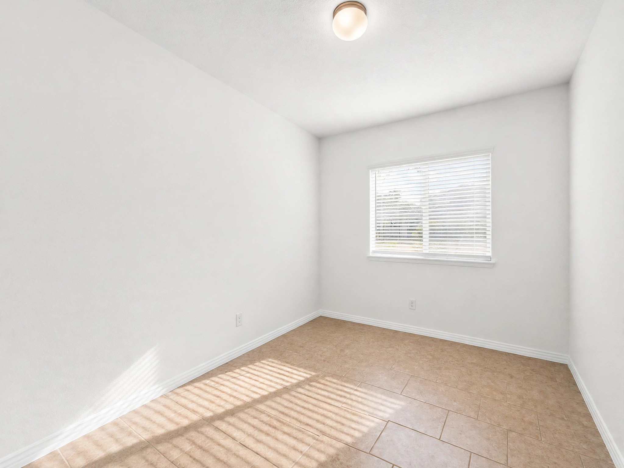 Unfurnished secondary bedroom showcases the ample space, tile flooring, and bright space.
