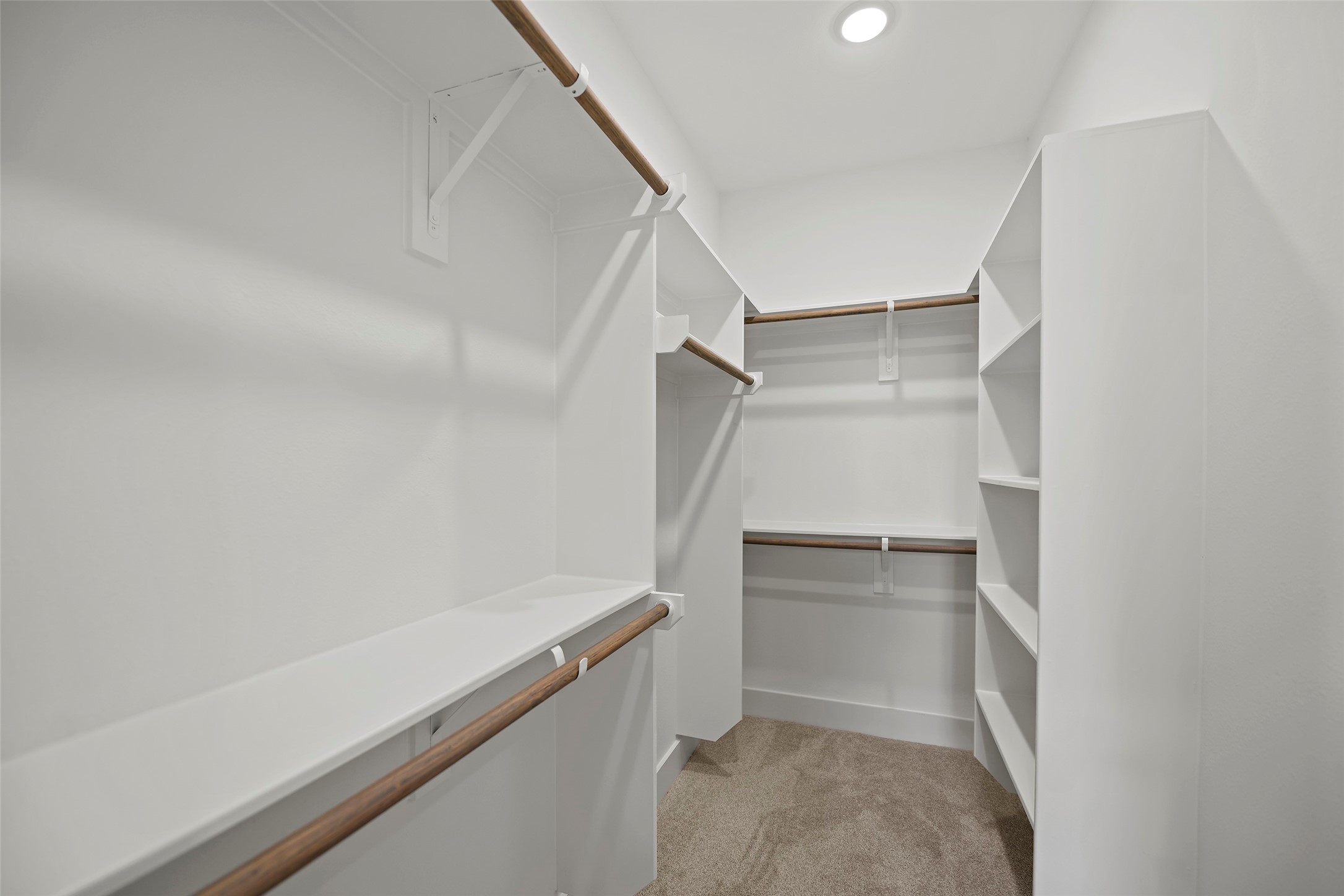 A spacious walk-in closet featuring multiple hanging rods, open shelving, and bright lighting, ideal for ample storage and organization.