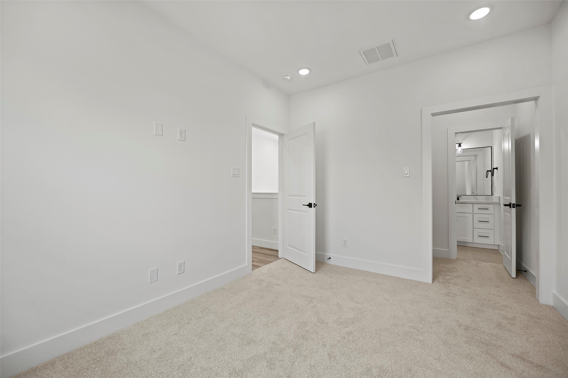 This secondary bedroom features recessed lighting, and a full bathroom with a vanity and walk-in closet.
