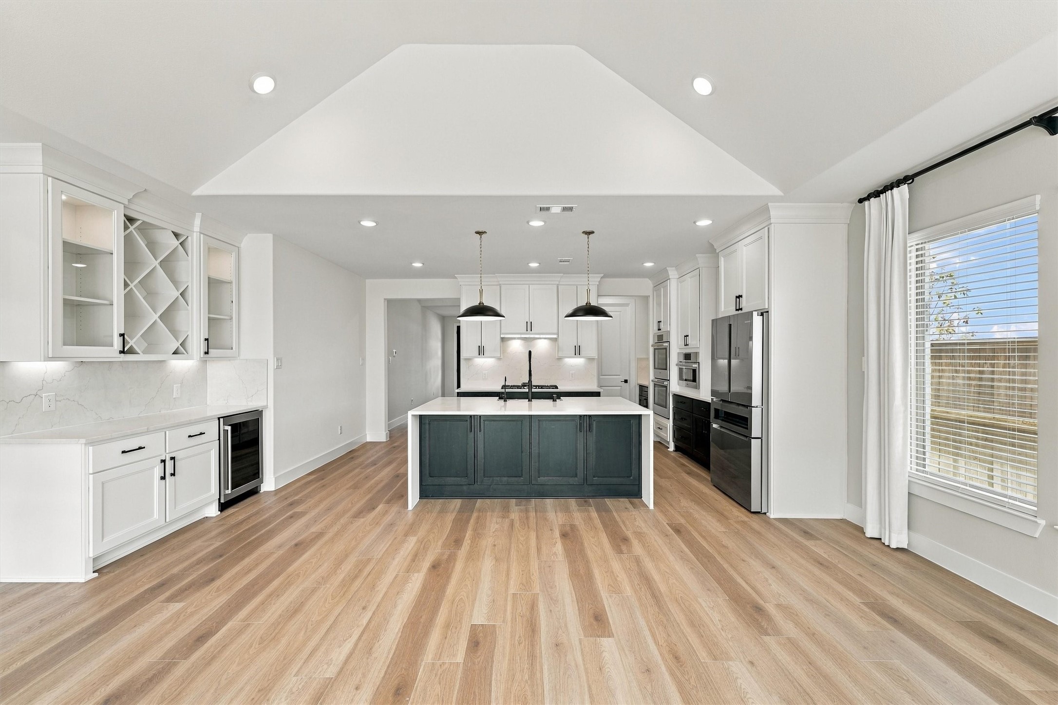 Glass-front cabinets, a diamond wine rack, and a beverage fridge make the dry bar a natural gathering spot beside the kitchen.