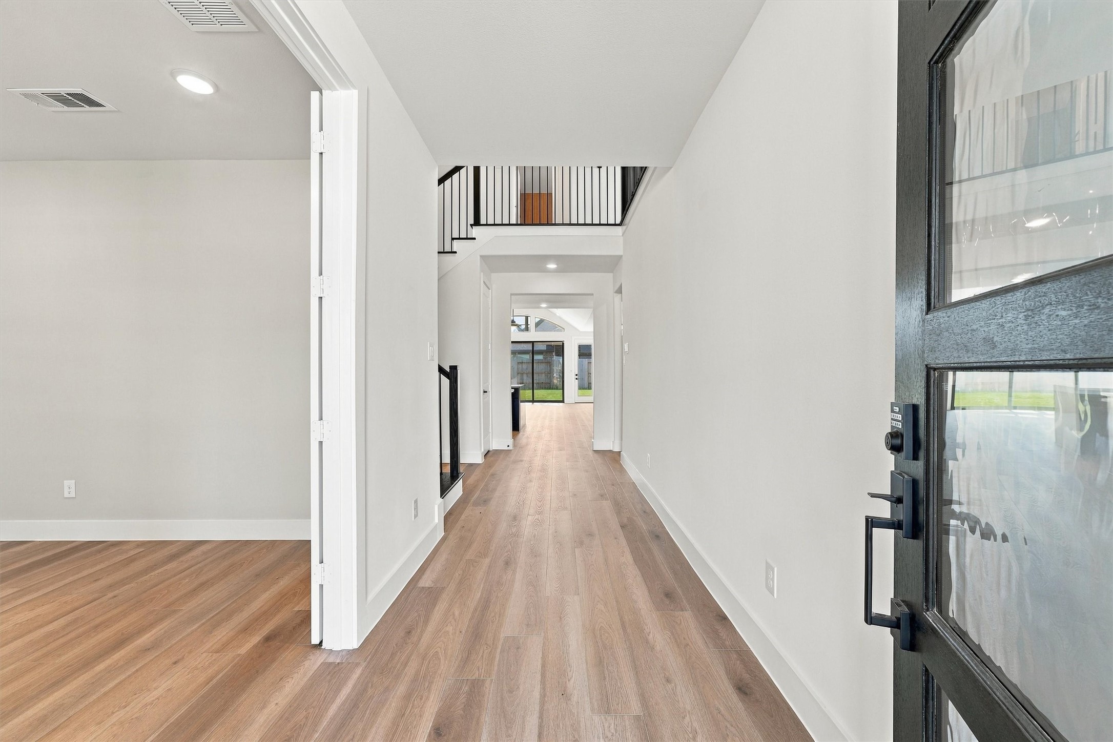 A gallery entry with an open stairwell and modern black balusters, and sightlines straight through to the backyard. A gallery entry with an open stairwell and modern black balusters, and sightlines straight through to the backyard.