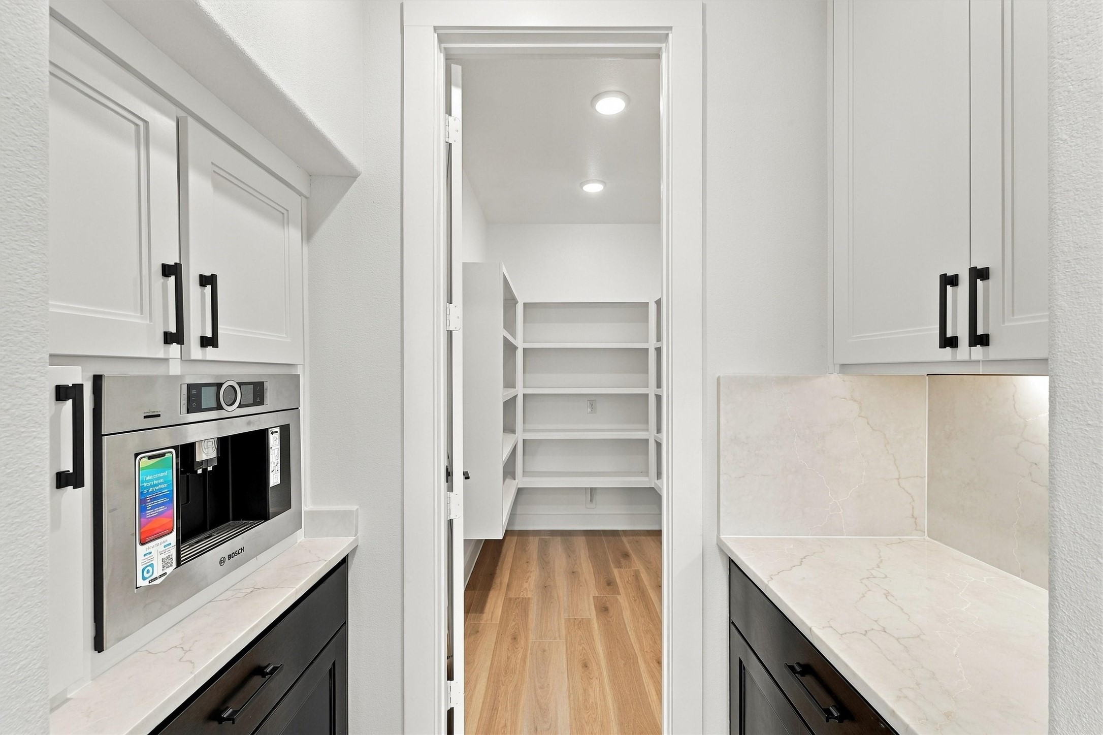 A built-in Bosch coffee system, quartz counters, and custom cabinetry lead to a walk-in pantry with floor-to-ceiling shelving.
