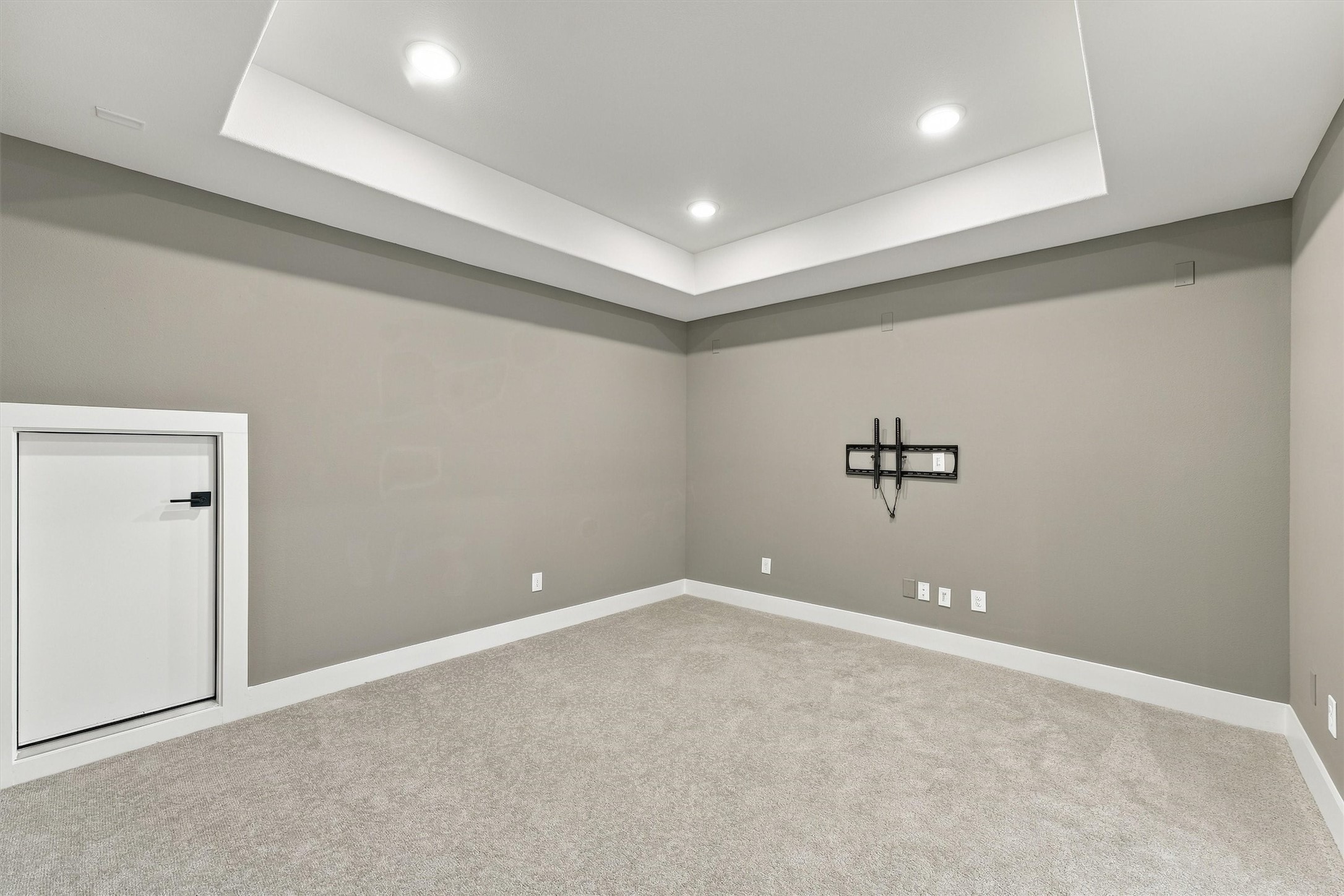 The media room has a tray ceiling with recessed lighting, a mounted TV bracket, and a convenient storage door.