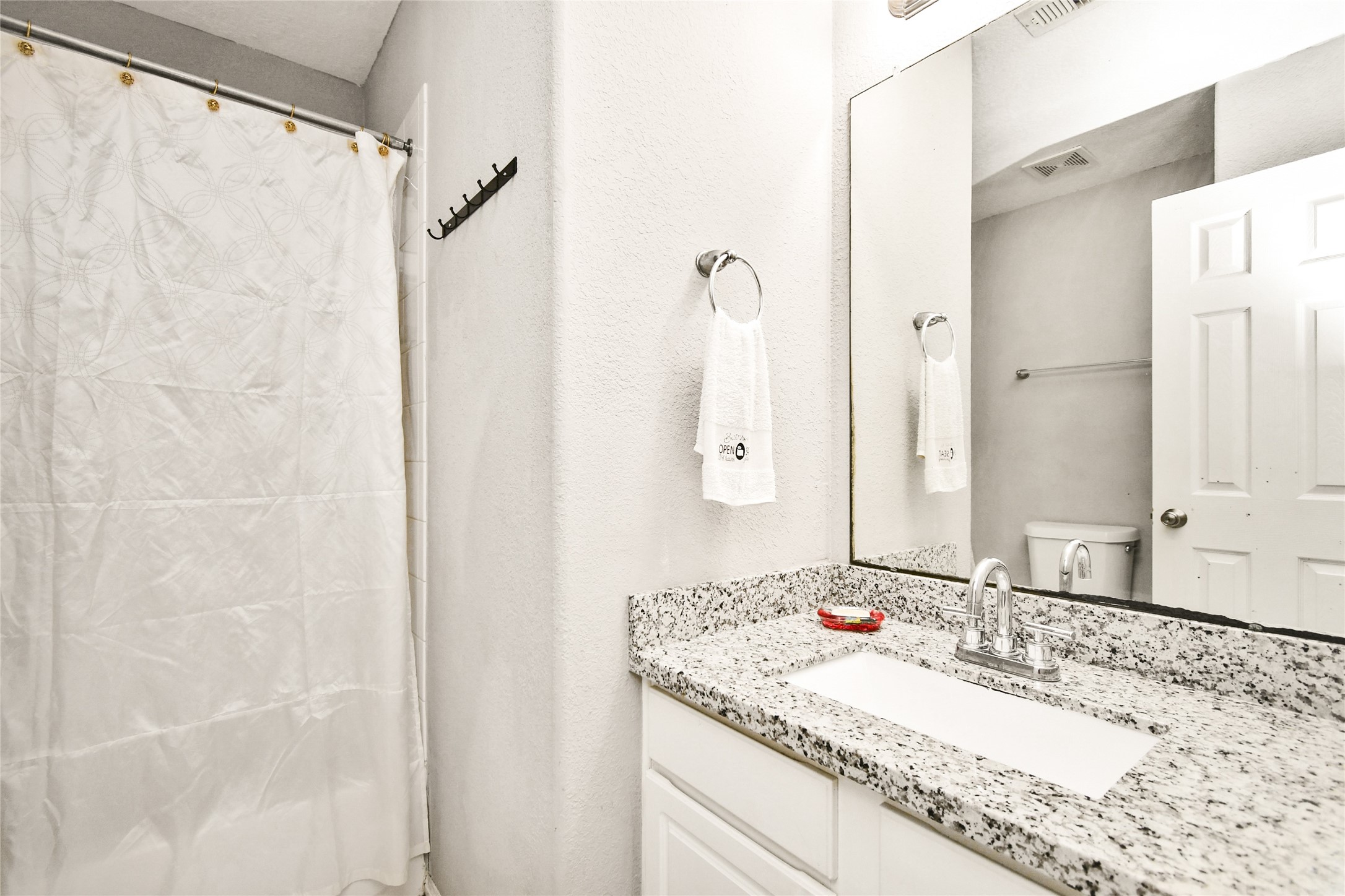 Updated bathroom vanity with granite countertop, modern fixtures, and ample mirror space.