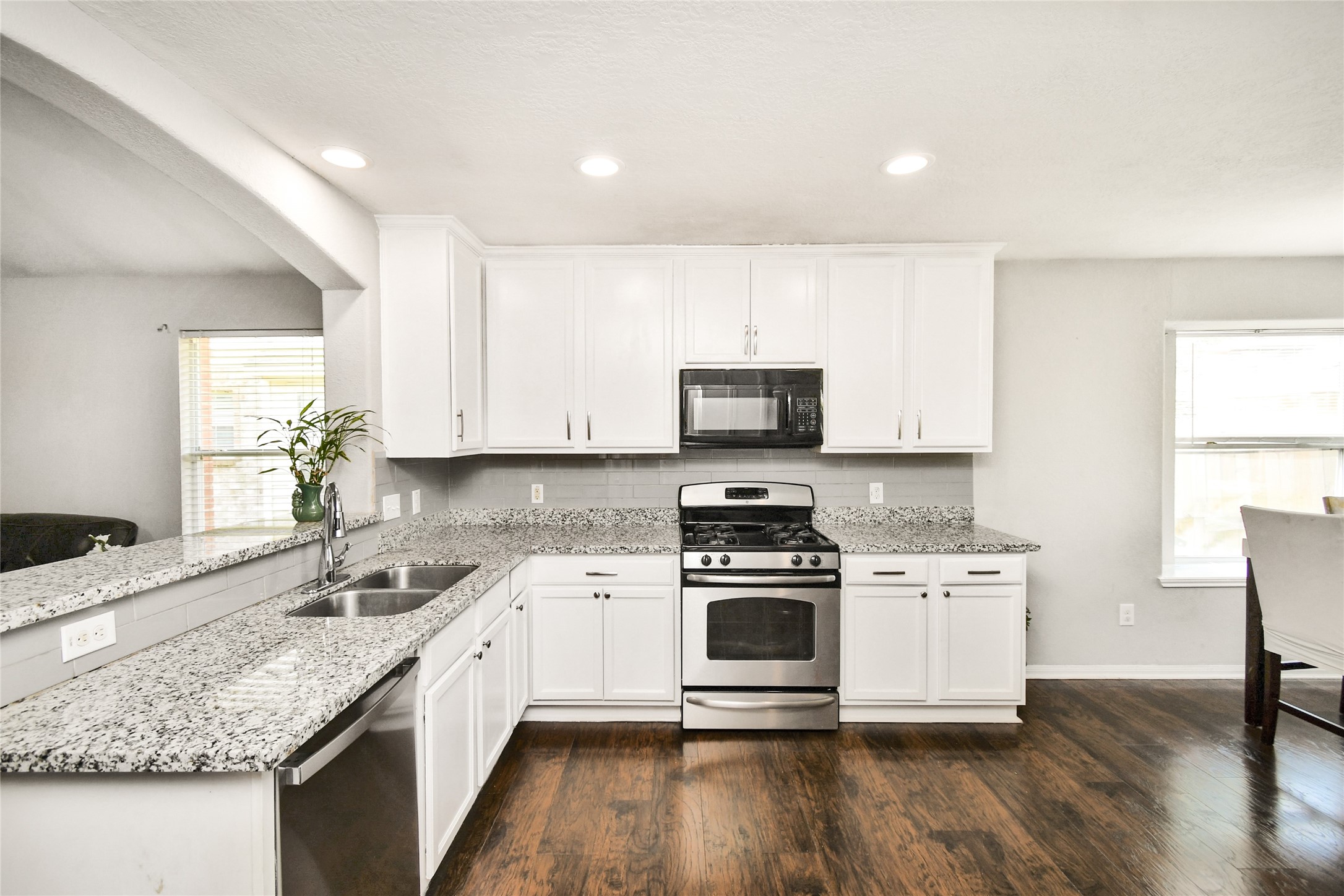 Well appointed kitchen featuring crisp white cabinets, granite counters, and a gas range.