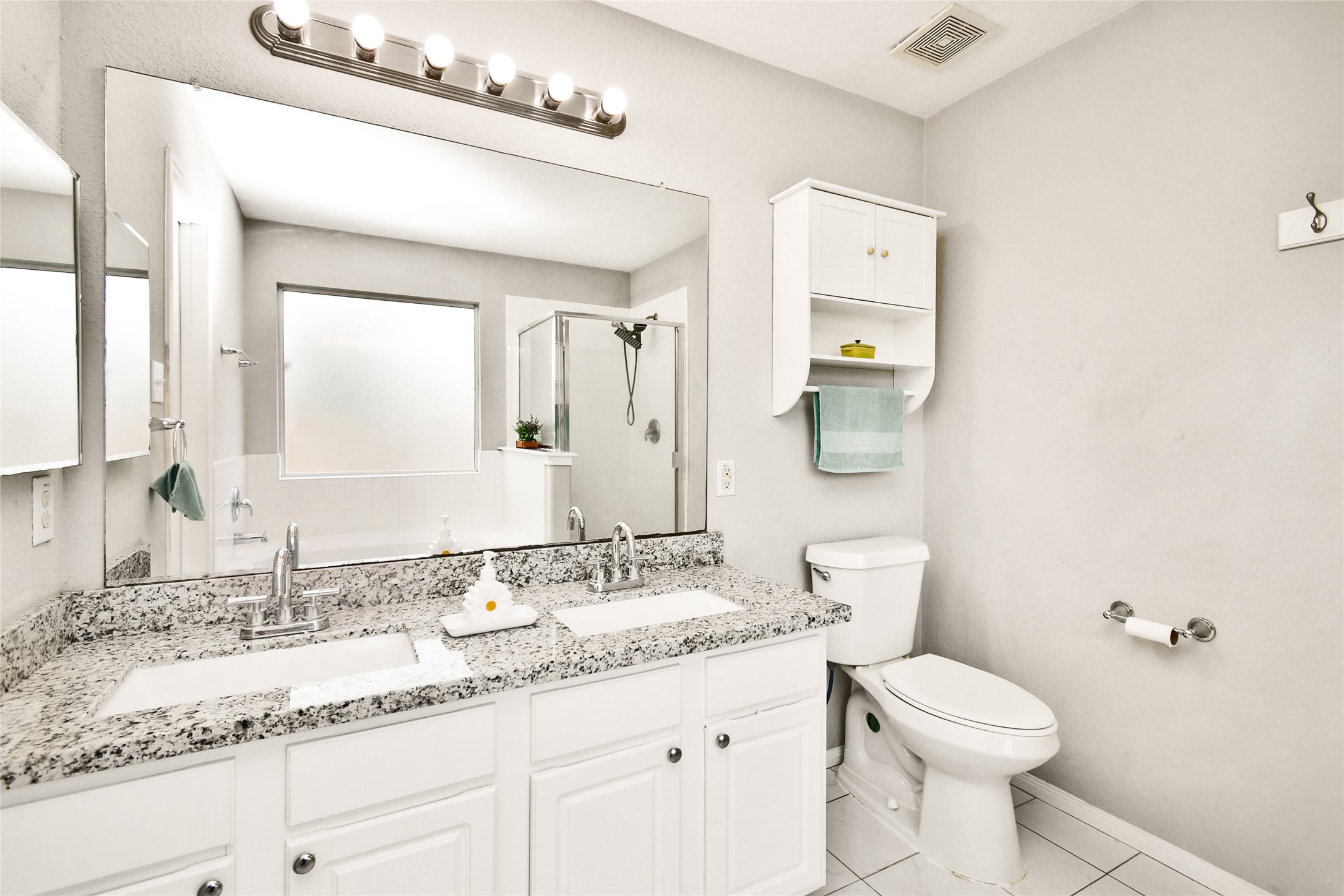 Elegant en suite bathroom with a granite double vanity, a walk-in shower, and a soaking tub.