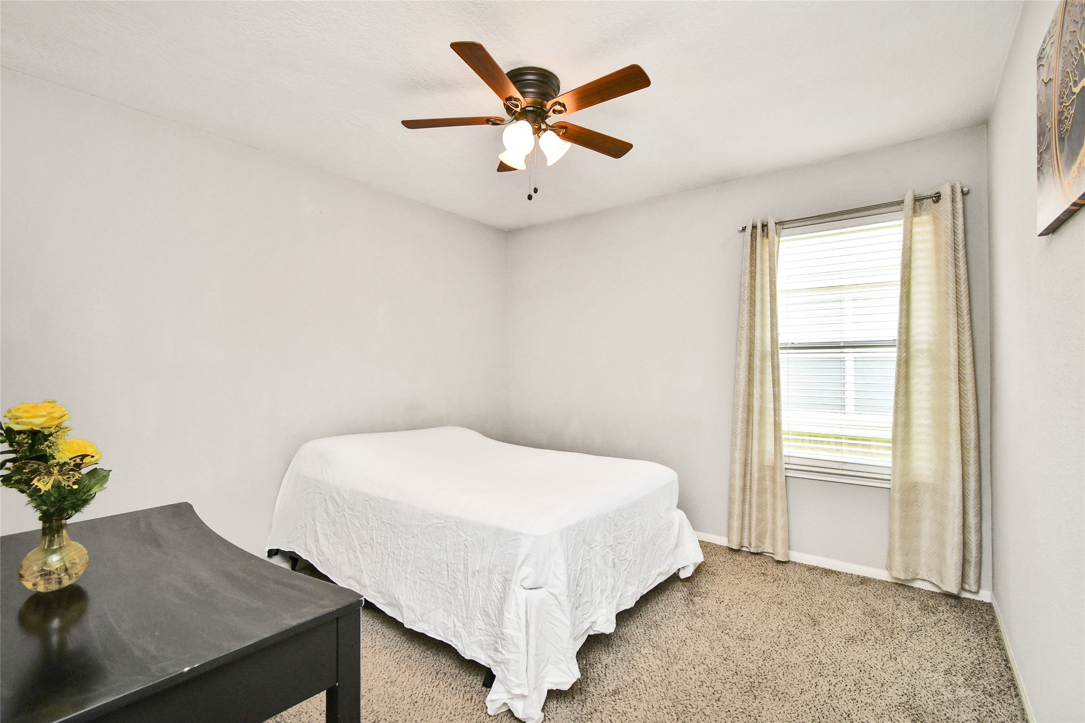 Inviting bedroom with large window, natural light, and plush carpet flooring.