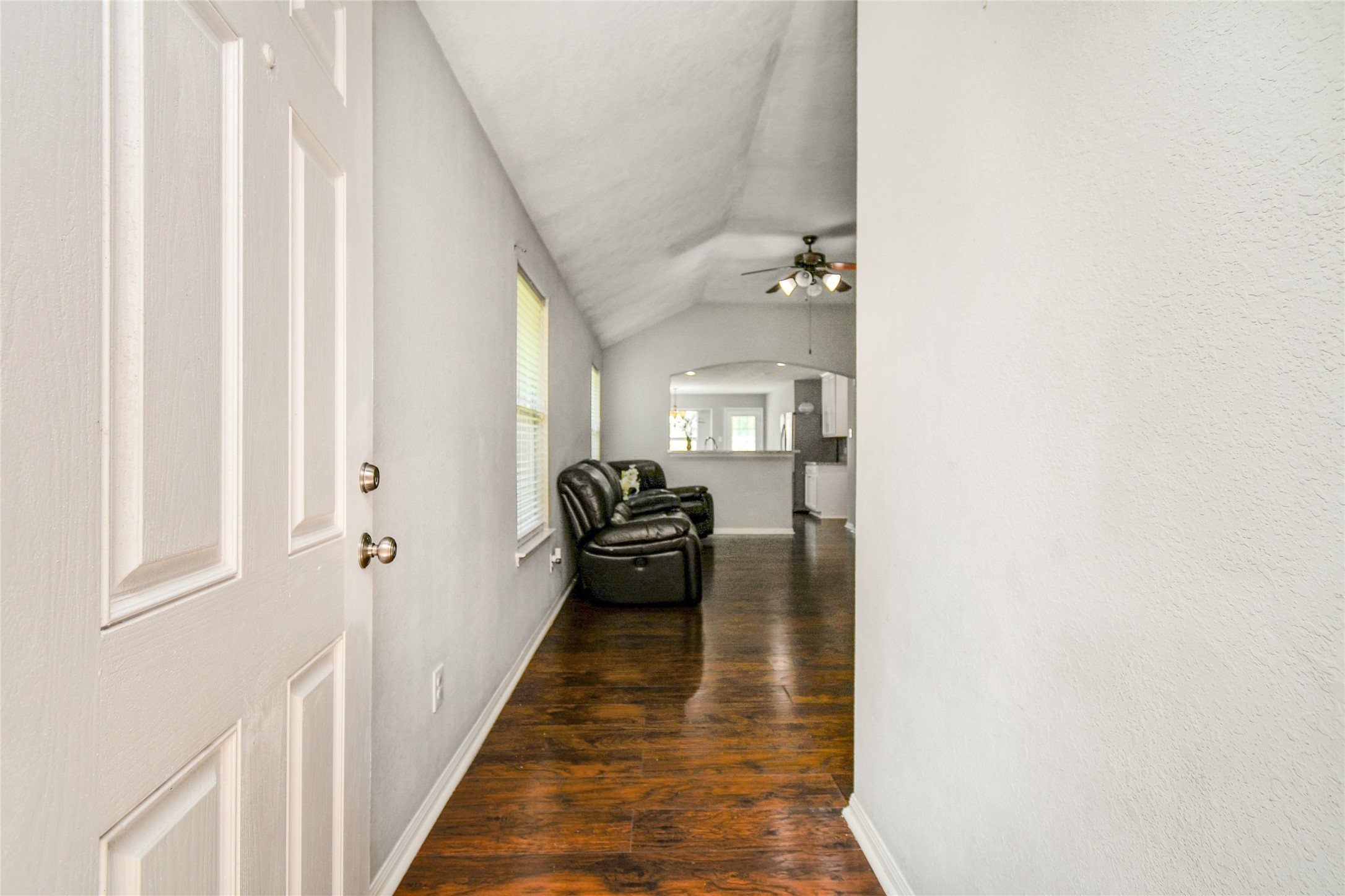 Bright entryway with soaring vaulted ceilings and rich wood look vinyl flooring that flows into the open living area.