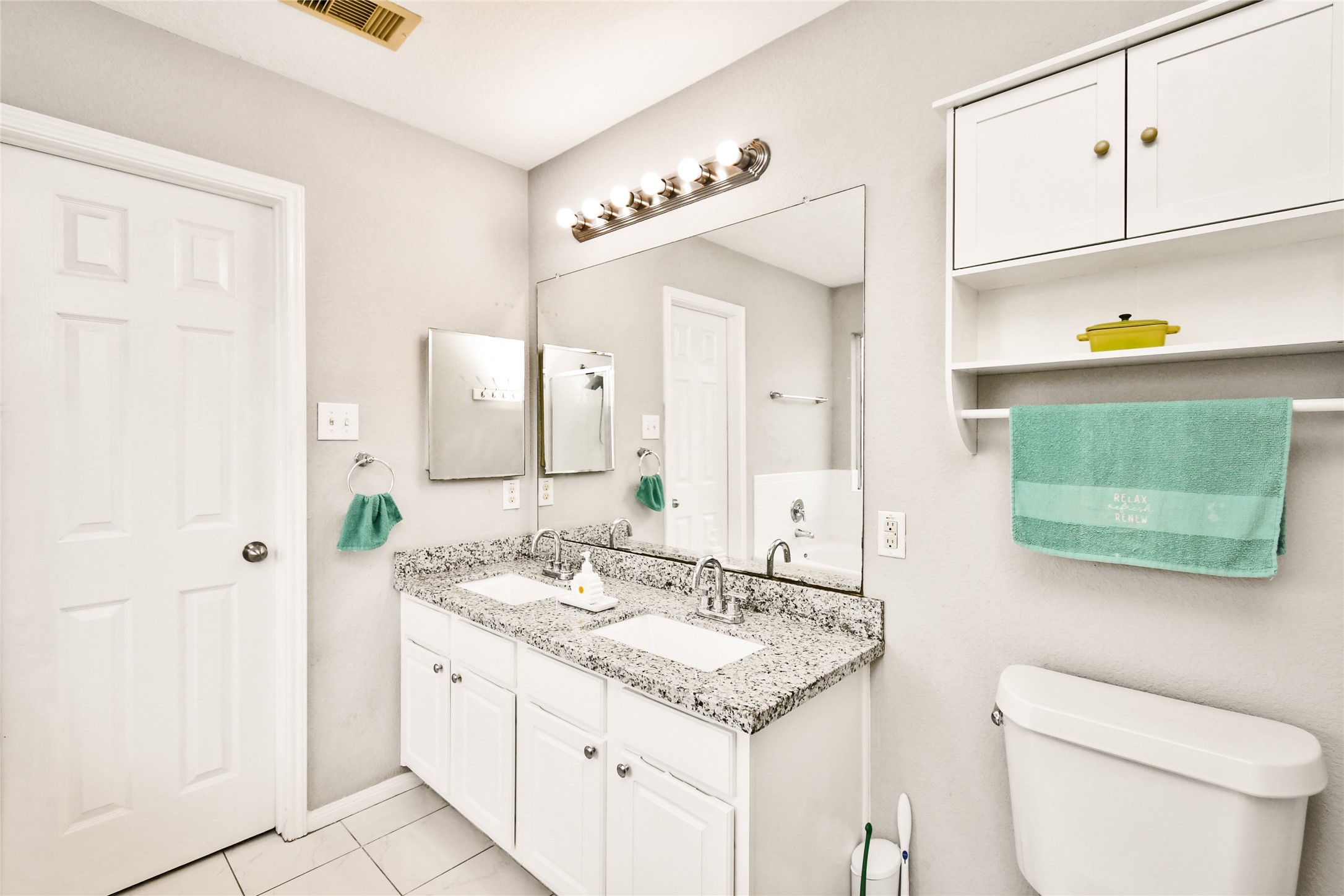 Bright en suite bathroom with double sinks, granite countertops, and ample storage.