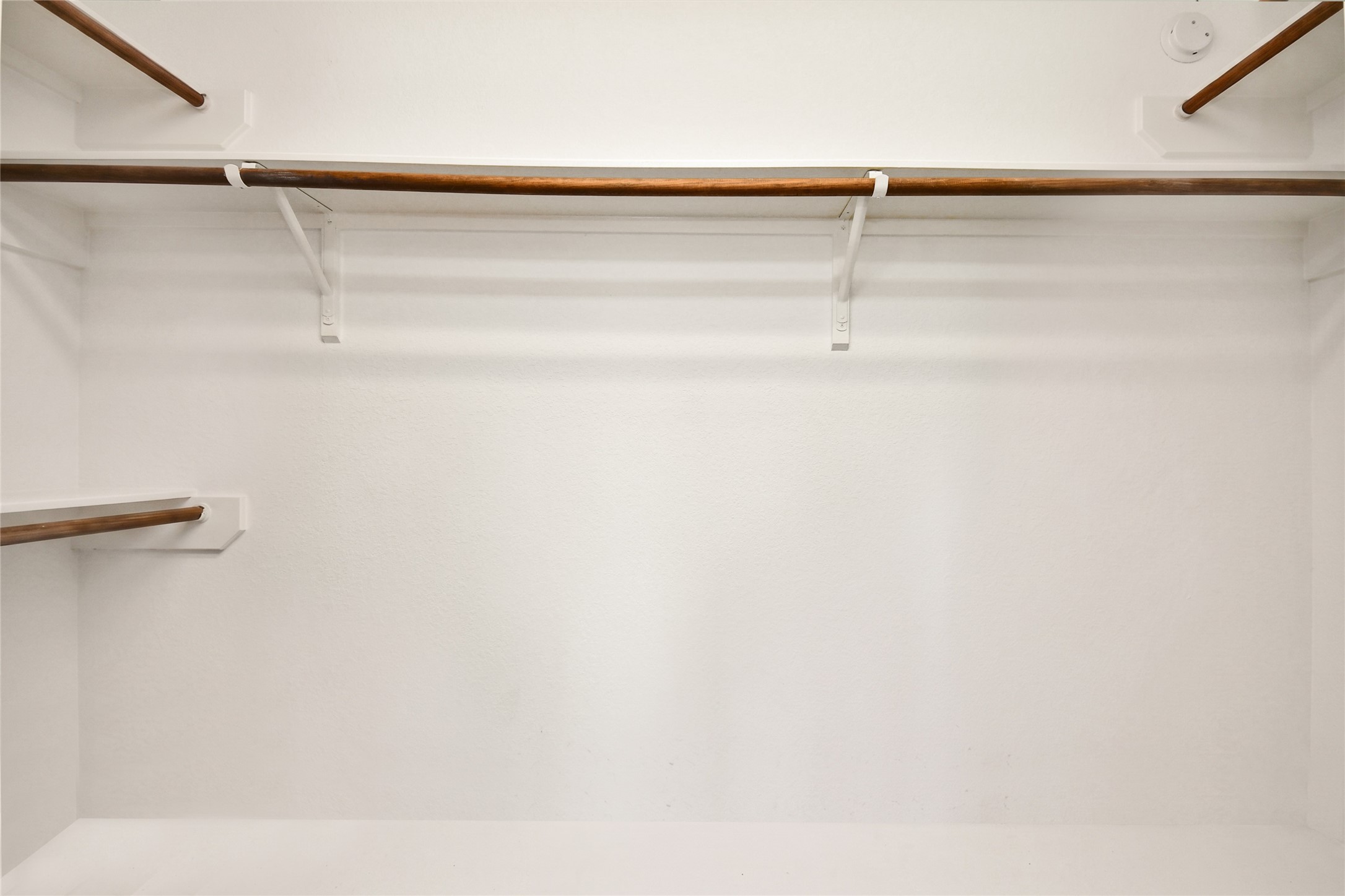 Spacious walk-in closet with double hanging rods, ready to fit a wardrobe of any size.