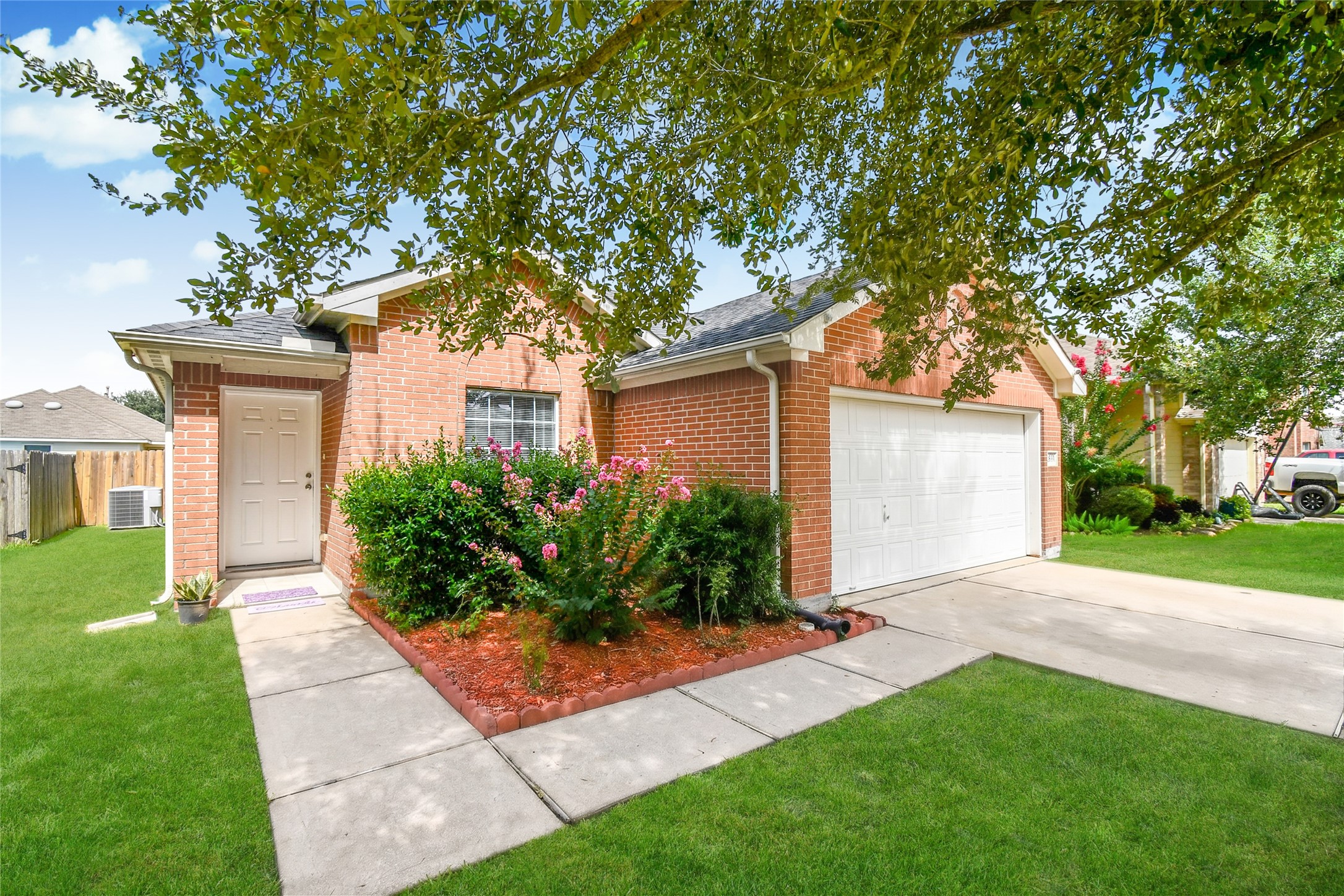 Beautiful curb appeal featuring a mature shade tree, blooming crape myrtles, and a well maintained brick exterior.