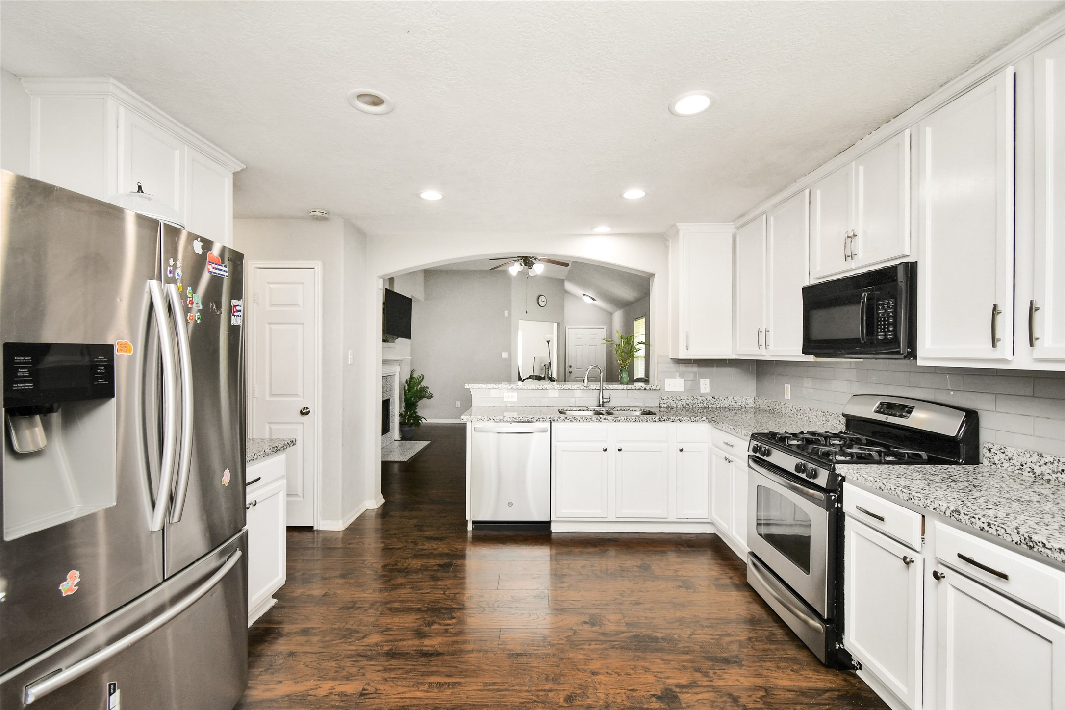 Open concept kitchen with stainless steel appliances flowing seamlessly into the living room.