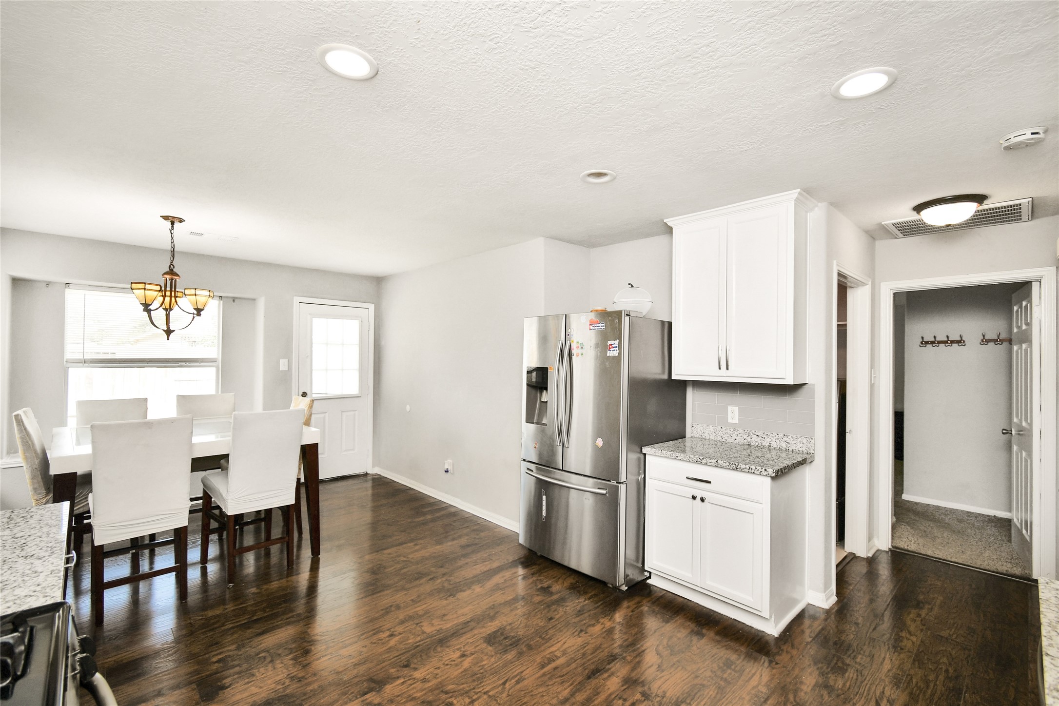 Functional kitchen layout with stainless steel refrigerator, ample cabinet storage, and access to the back entry.