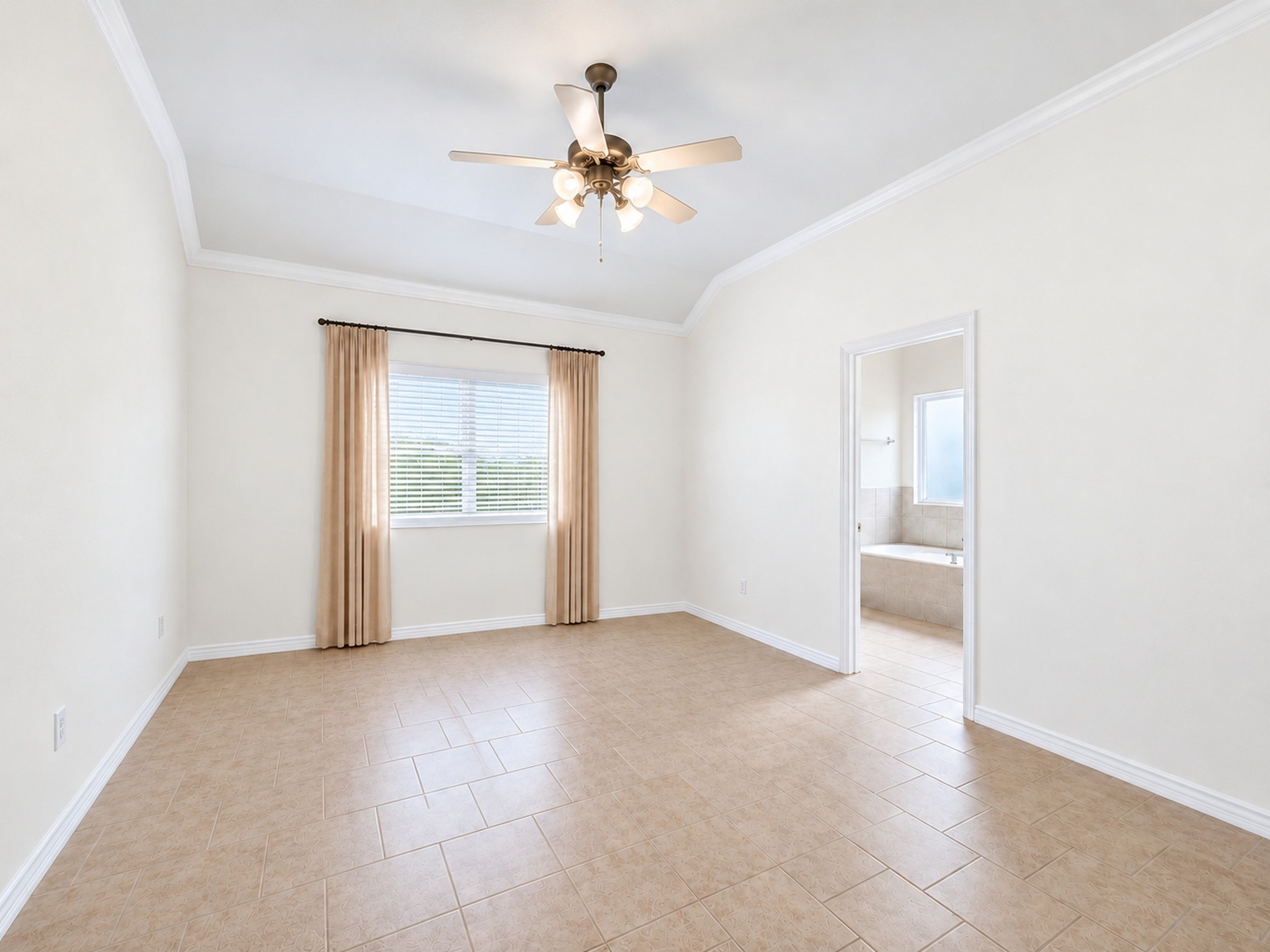 Unfurnished bedroom view shows the tray ceiling, ceiling fan, and adjoining bathroom access.