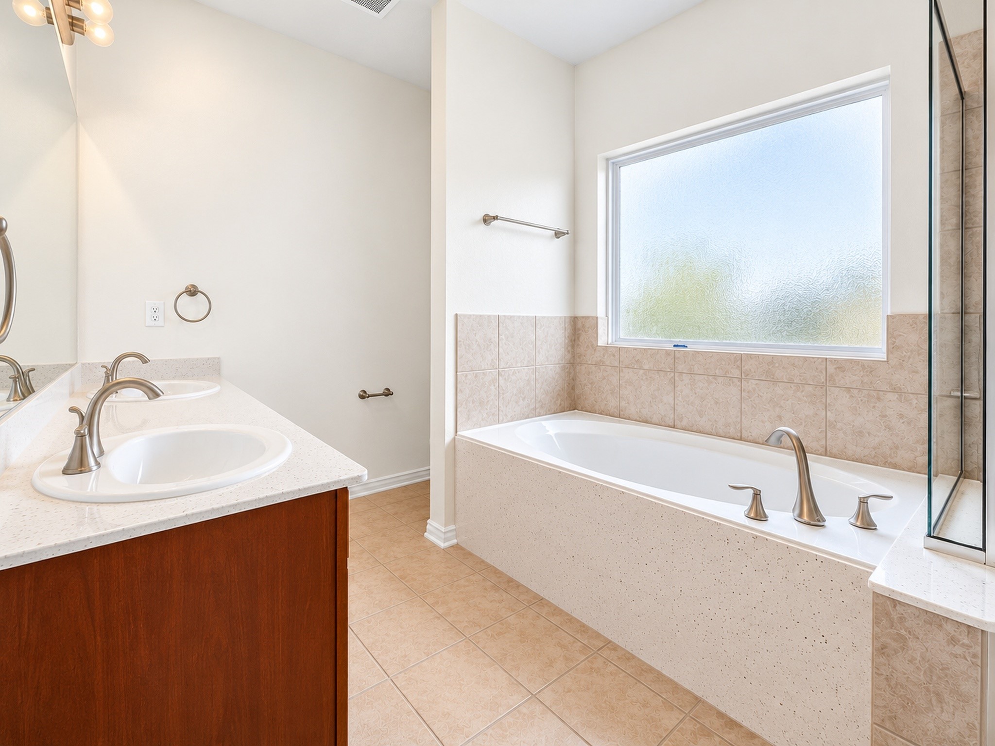 Bathroom view featuring a soaking tub, separate shower, vanity, and large window.