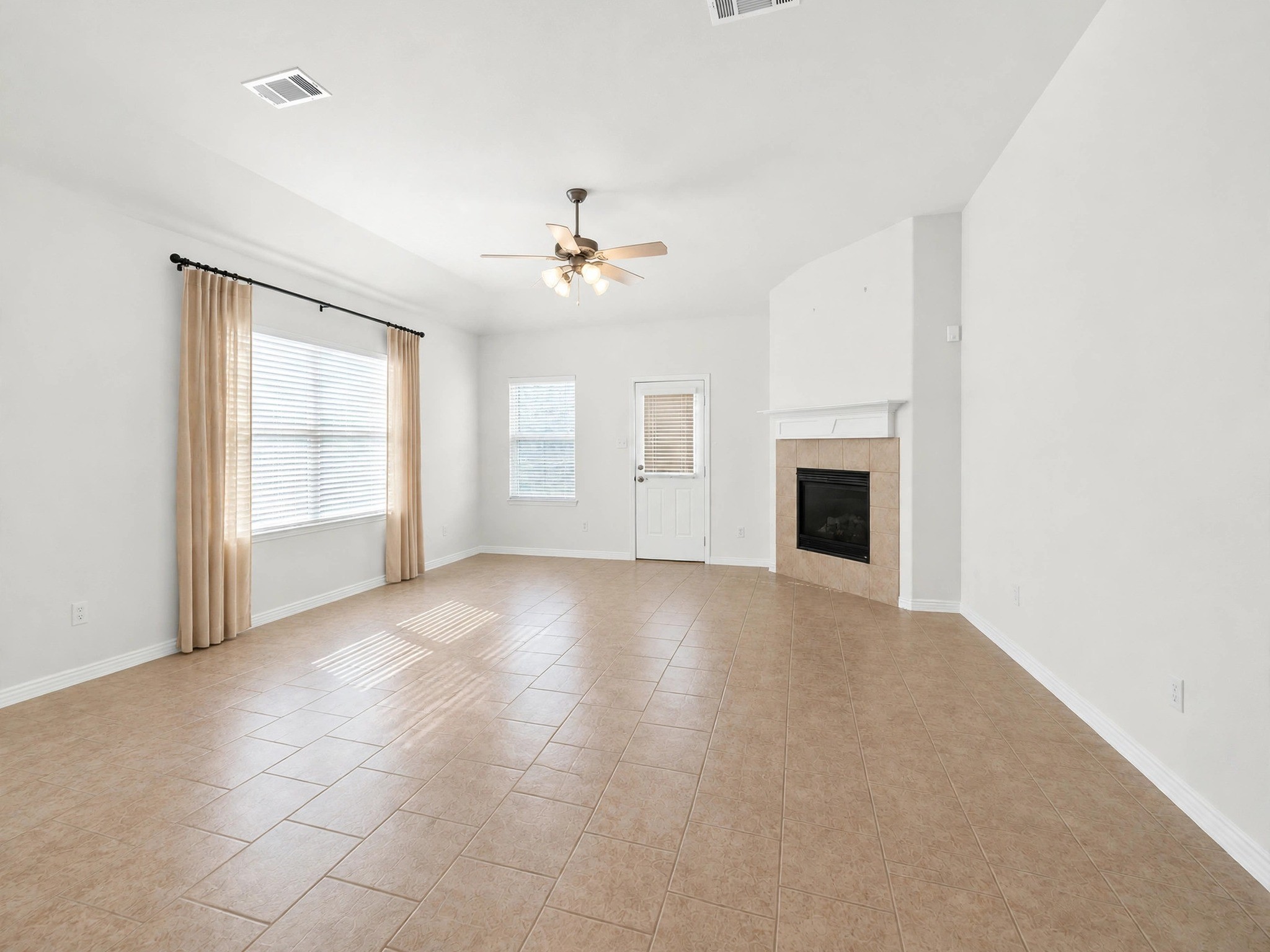 Spacious living area with a fireplace, ceiling fan, and large windows overlooking the backyard. Spacious living area with a fireplace, ceiling fan, and large windows overlooking the backyard.